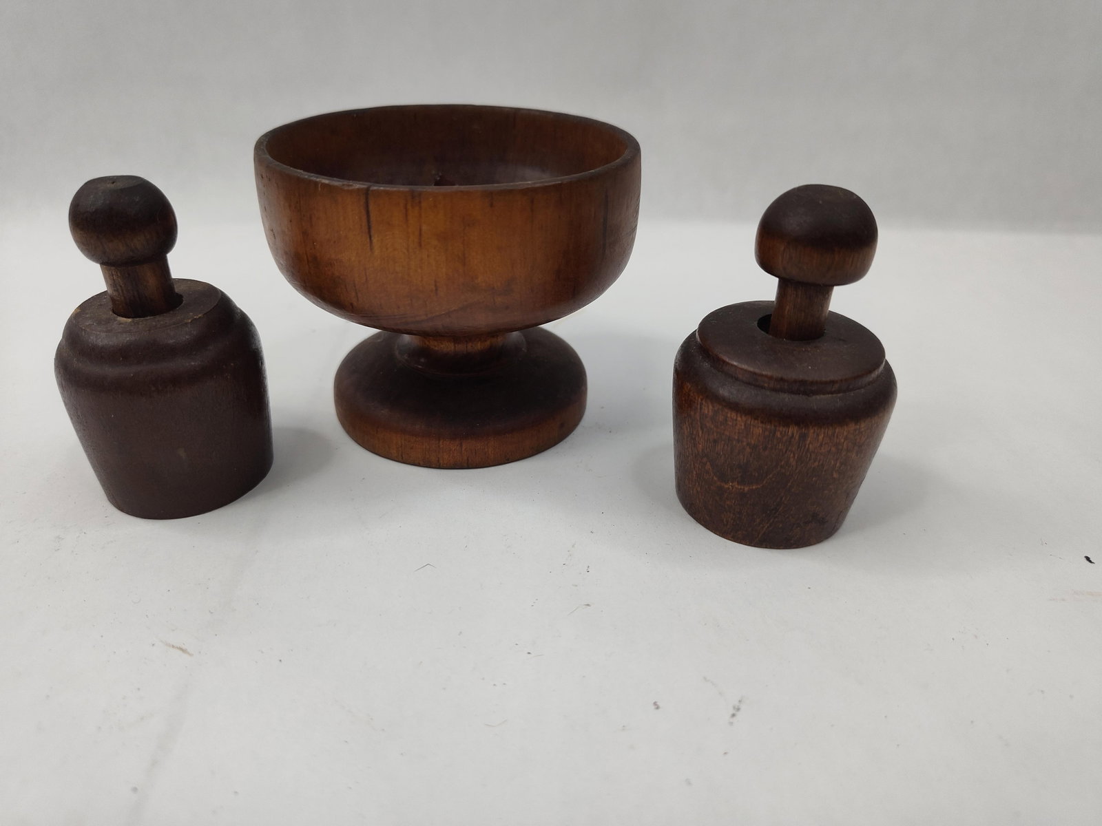 3 Treenware Pieces: Compote & Stamps: This group of hand-turned wooden objects features a dark-stained finish throughout. The collection includes a pedestal compote bowl and two butter stamps with protective sleeves. The compote bowl is