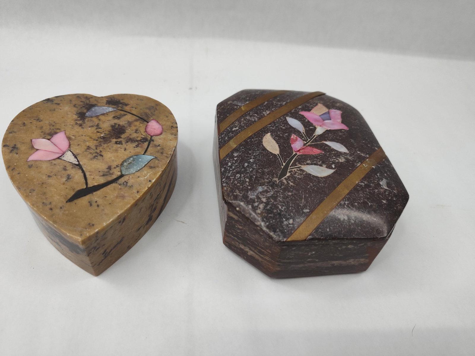 Pair Indian Carved Stone & Shell Boxes: Two Indian hand-carved stone trinket boxes featuring decorative shell inlay. The first piece is a heart-shaped box crafted from a mottled tan and brown stone, possibly soapstone. The lid is decorated 