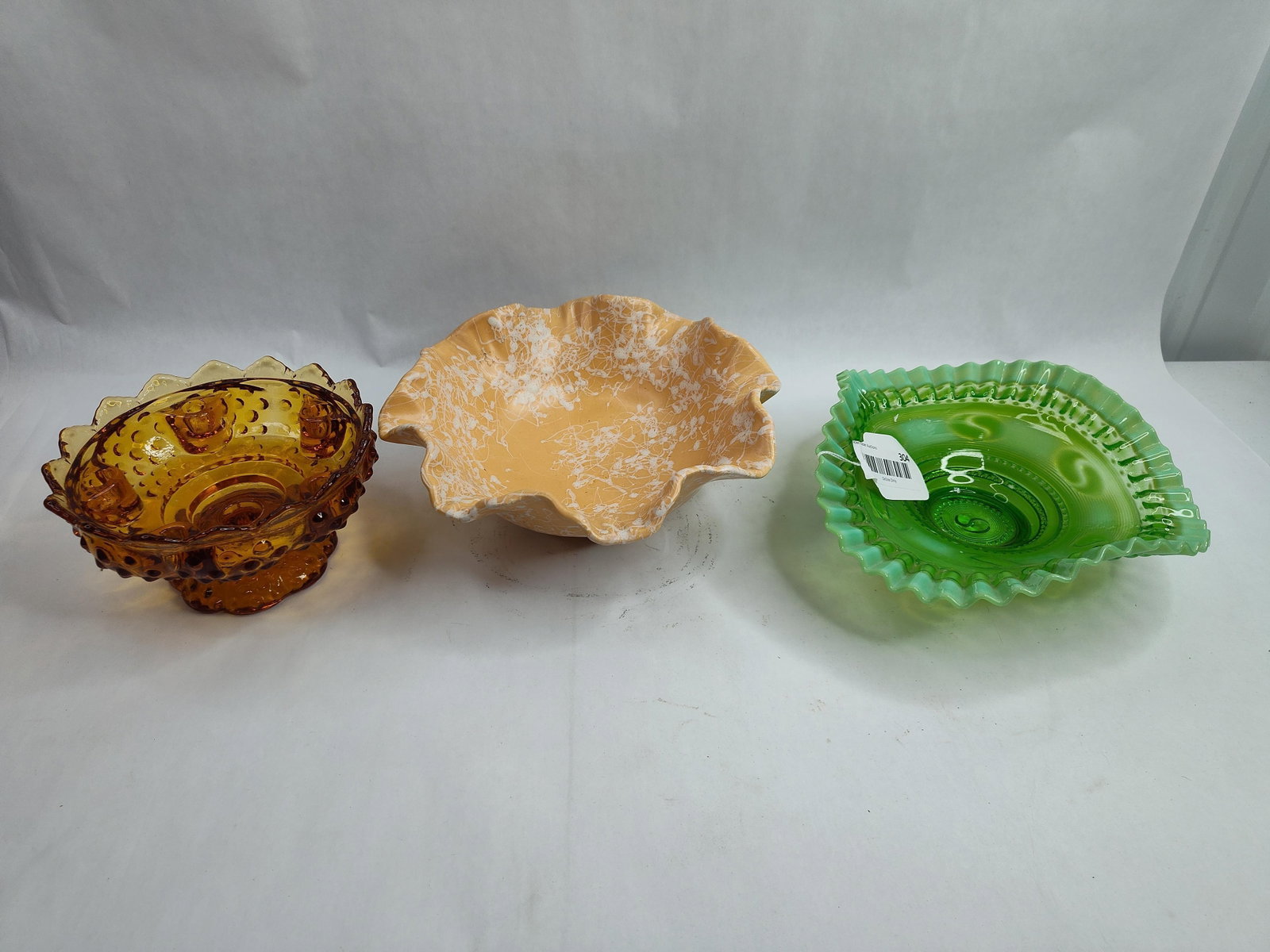 3 American Glass & Ceramic Bowls: A trio of decorative mid-century American bowls comprising two glass examples and one ceramic vessel. The first is an amber-colored pressed glass pedestal bowl featuring a hobnail pattern with a