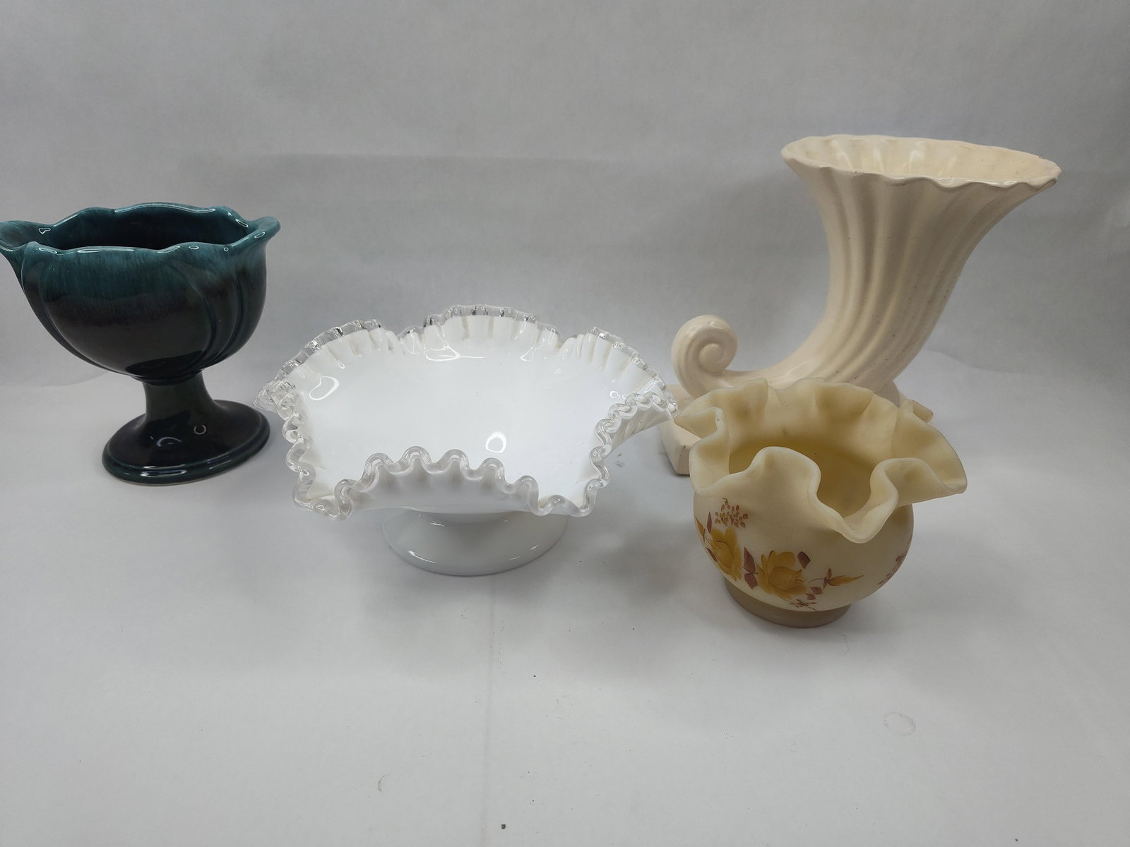 Ceramic and Glass Decorative Vessels: This assortment of decorative objects includes four distinct pieces of ceramic and glass. One piece is a teal and deep blue drip-glazed ceramic footed bowl featuring a lobed, ruffled rim. The