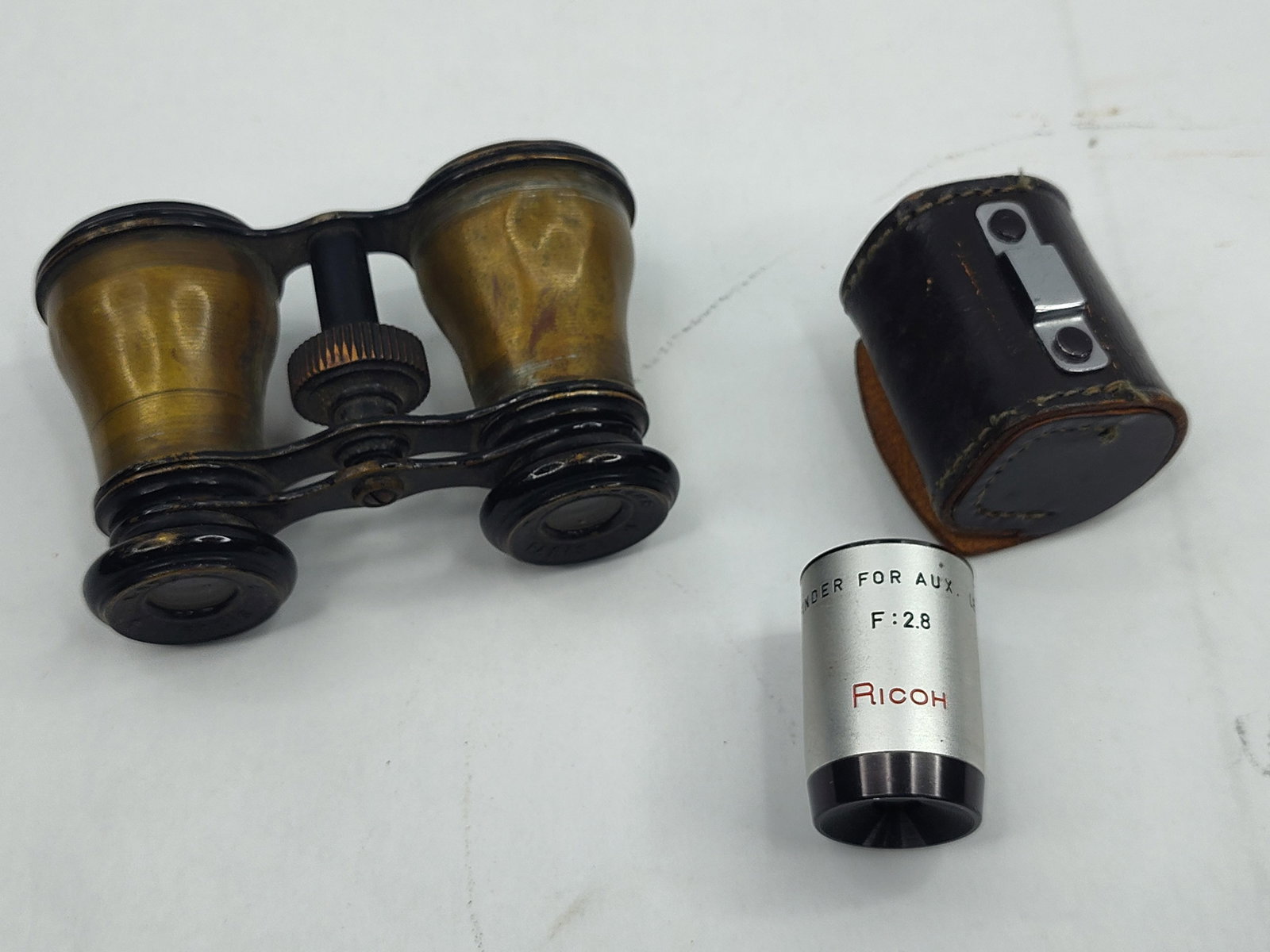 Latour Brass Opera Glasses & Ricoh Lens: A group of optical instruments comprising a pair of French theater binoculars and a photographic accessory. The opera glasses are constructed of brass with a center-focus wheel and black-painted