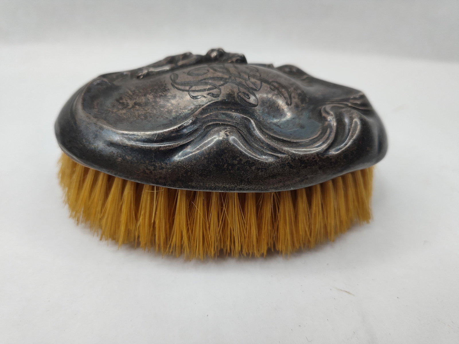 Art Nouveau Str. Mermaid Clothes Brush: An Art Nouveau sterling silver clothes brush featuring an oval mount with a repousse design of a mermaid emerging from stylized swirling waves and aquatic foliage. The center of the silver cover is