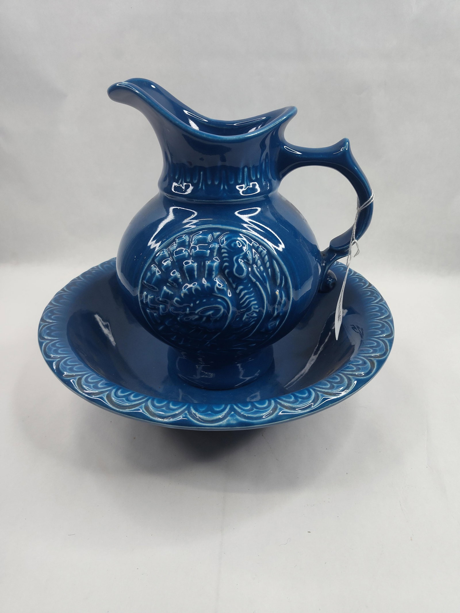 McCoy Pottery Turkey Pitcher & Basin: An American ceramic wash pitcher and basin set featuring a deep cobalt blue glaze. The pitcher is molded with a prominent embossed motif on both sides depicting a turkey with its tail feathers fanned