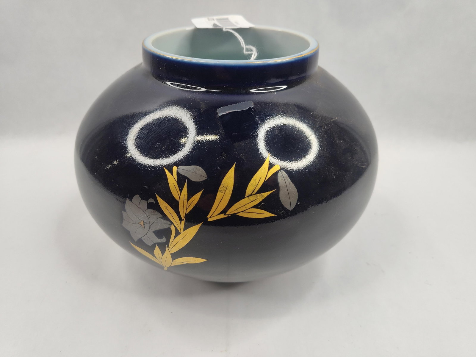 Japanese Porc. Vase w/ Bamboo & Lily: This Japanese porcelain vase is of globular form with a short neck, narrow opening, and gilded rim. The exterior is finished in a deep cobalt blue glaze, while the interior features a pale