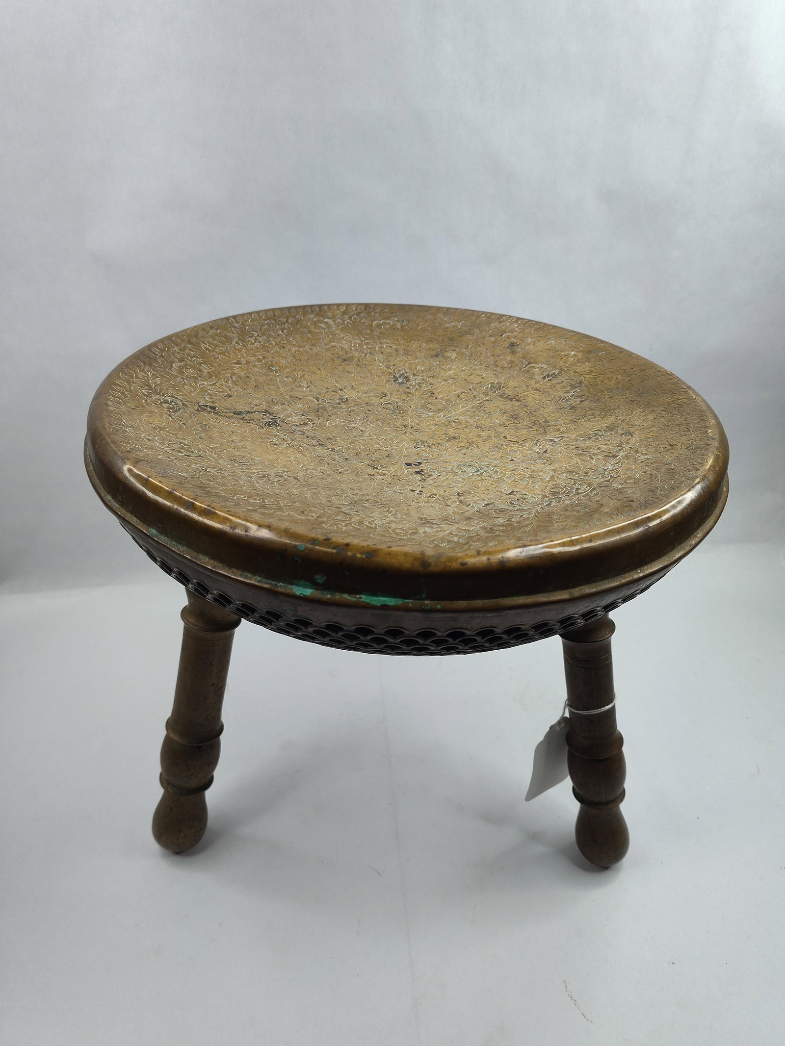 Mid-East Pierced Brass Foot Warmer: A three-legged brass stool or brazier, designed for use as a foot warmer. The circular top features a dense, hand-chased foliate and floral design organized around a central radiating floral