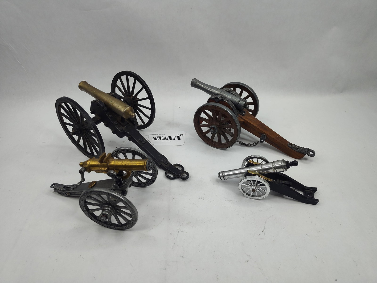 Set Miniature & Model Cannons: A group of various miniature and model cannons and field pieces of mixed construction. The collection includes a field gun with a brass barrel mounted on a black cast metal carriage; the underside of 