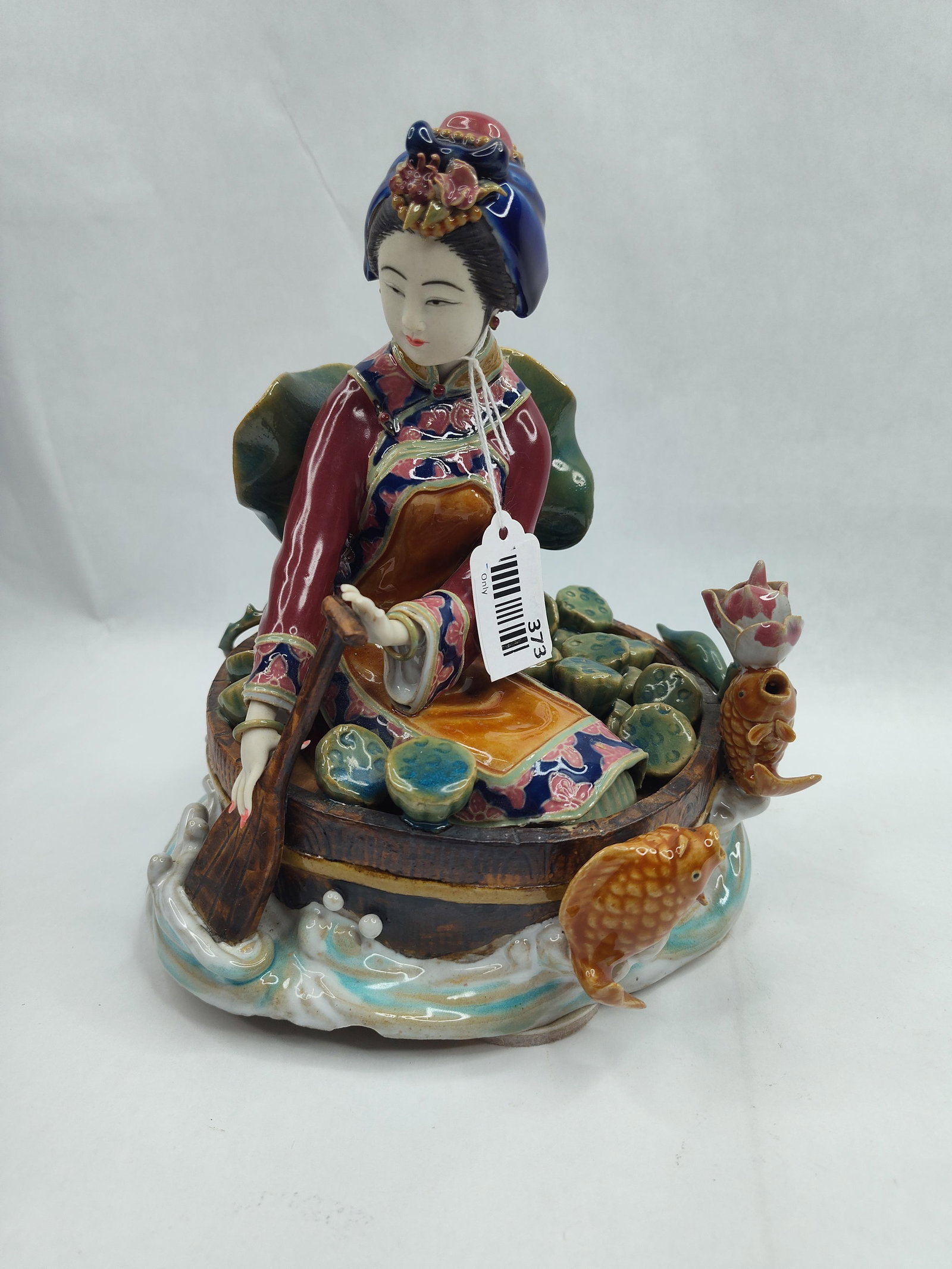 Chinese Shiwan Porc. Lotus Gatherer: A Chinese polychrome porcelain figural grouping executed in the Shiwan style, depicting a young woman in traditional Manchu-style dress. The figure is modeled wearing a dark blue headdress with