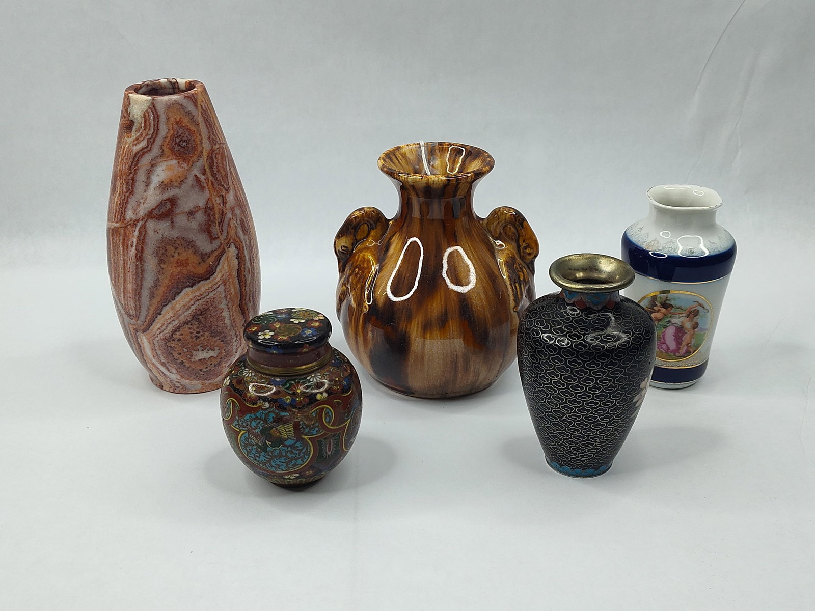 Set Cloisonne & German Porc. Vases: A collection of various miniature decorative vessels in diverse materials and styles. The grouping includes a tall, tapered vase crafted from polished banded red and white onyx. Two items feature