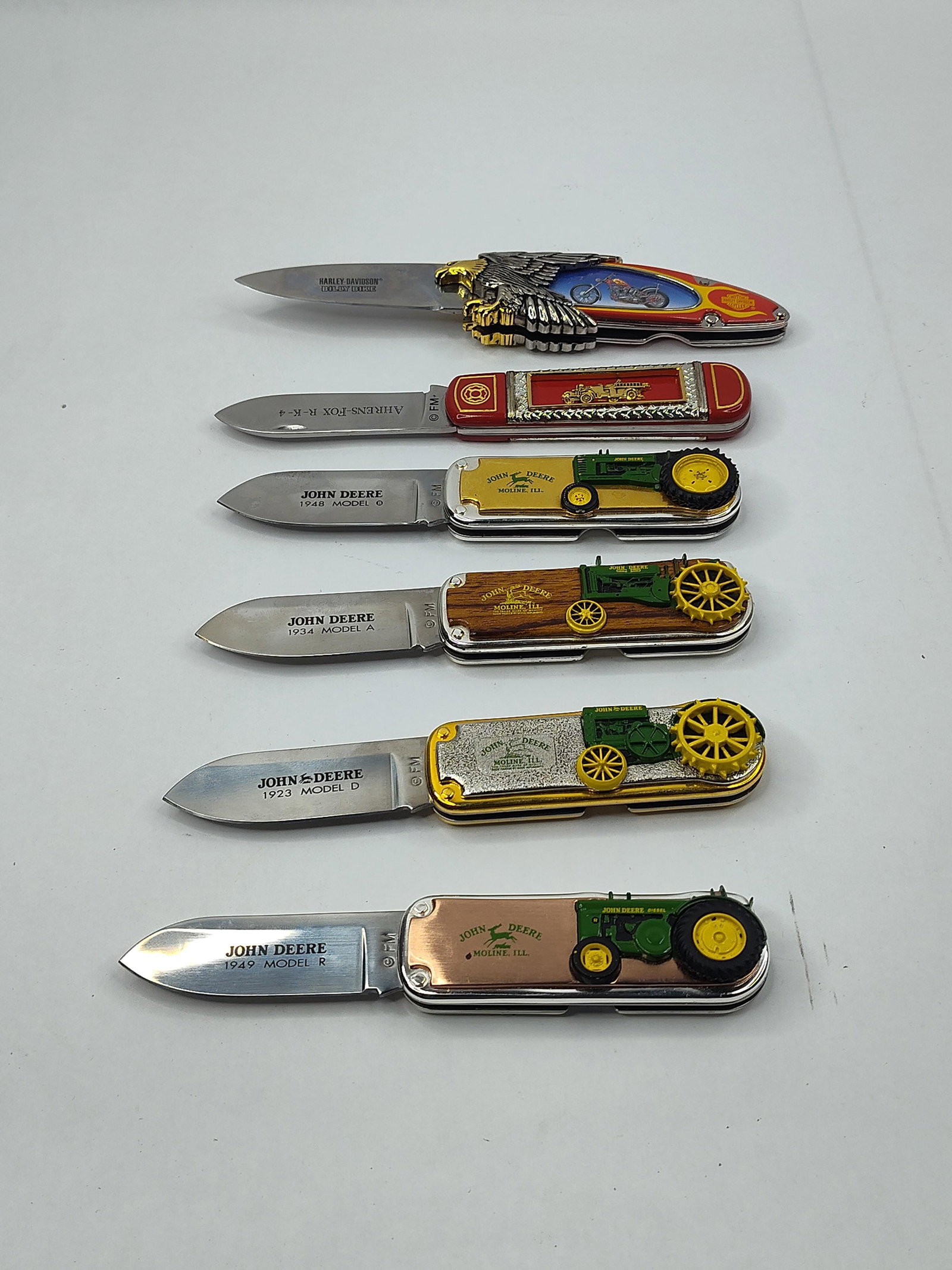 Franklin Mint Collector Knives, Set: An assortment of themed folding pocket knives manufactured by Franklin Mint. The collection prominently features several knives commemorating John Deere tractor models, including a 1948 Model B, 1934