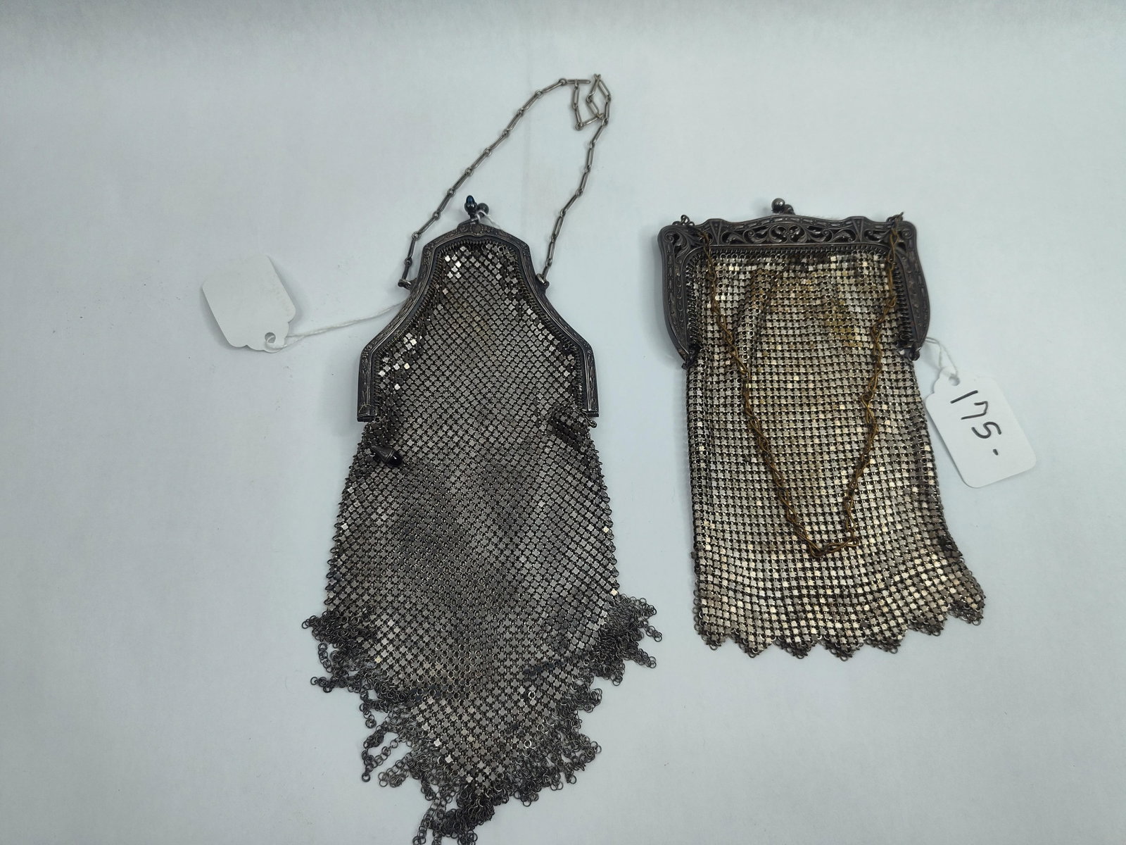 Two Whiting and Davis Metal Mesh Purses: Two silver-toned armor mesh evening bags featuring decorative metal frames and chain handles. The first purse has a rectangular profile with an ornate openwork Art Nouveau-style frame decorated with
