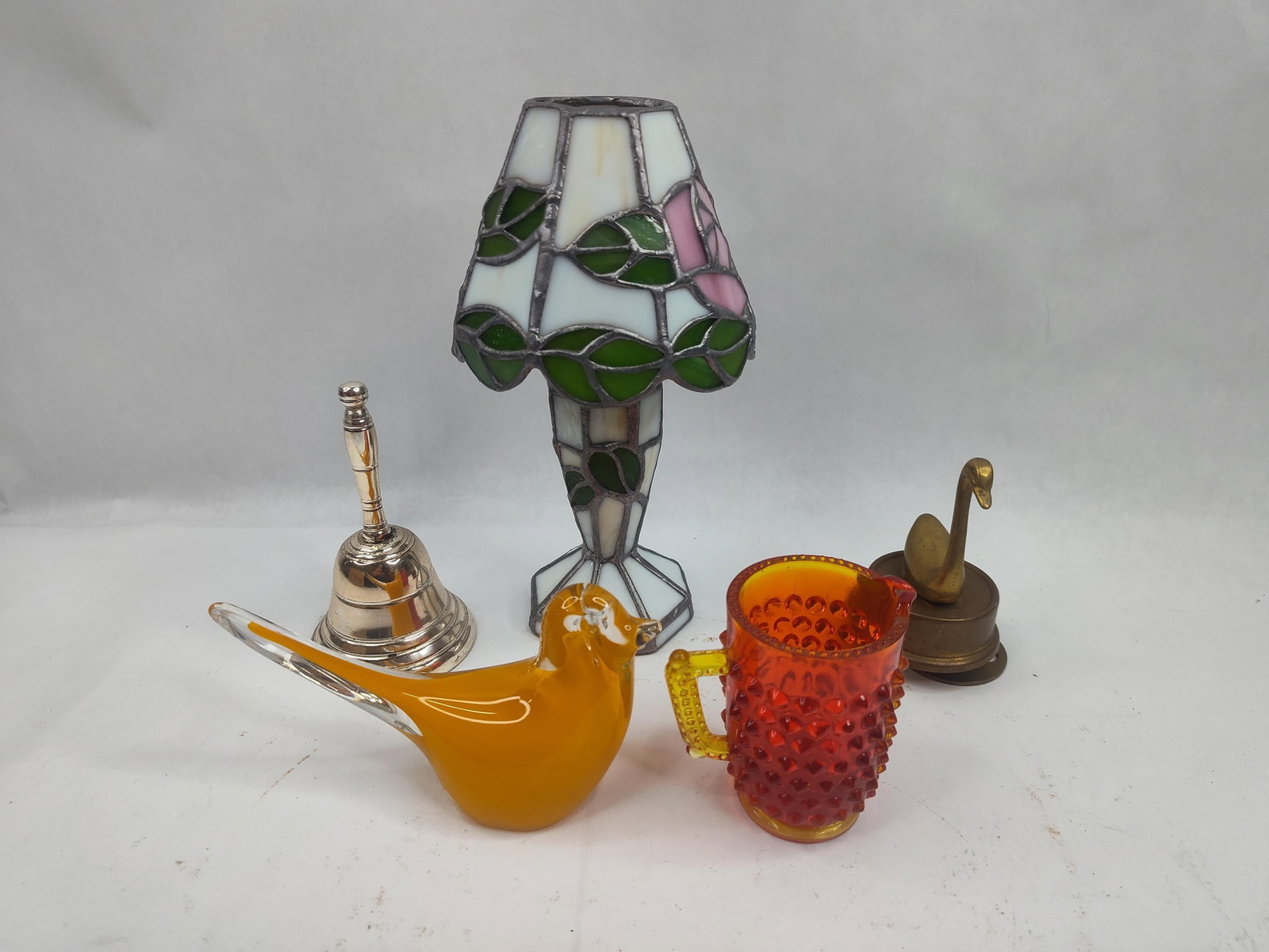 Stained Glass & Table Objects: A collection of decorative items featuring a miniature Tiffany-style table lamp constructed with a leaded glass shade and matching base. The stained glass features a floral motif of pink roses and gre