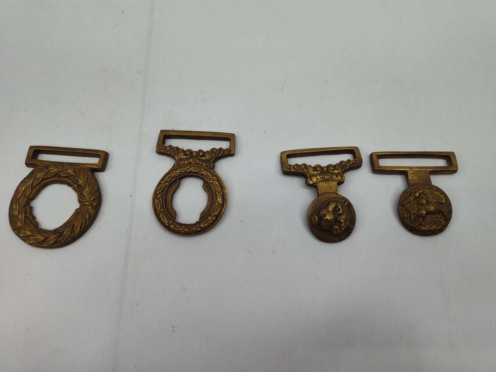 Brass Military & Naval Belt Slides/Loop: A collection of cast brass belt components, likely of British military or naval origin from the late 19th or early 20th century. The group comprises two wreath-style loops and two T-bar belt slides.