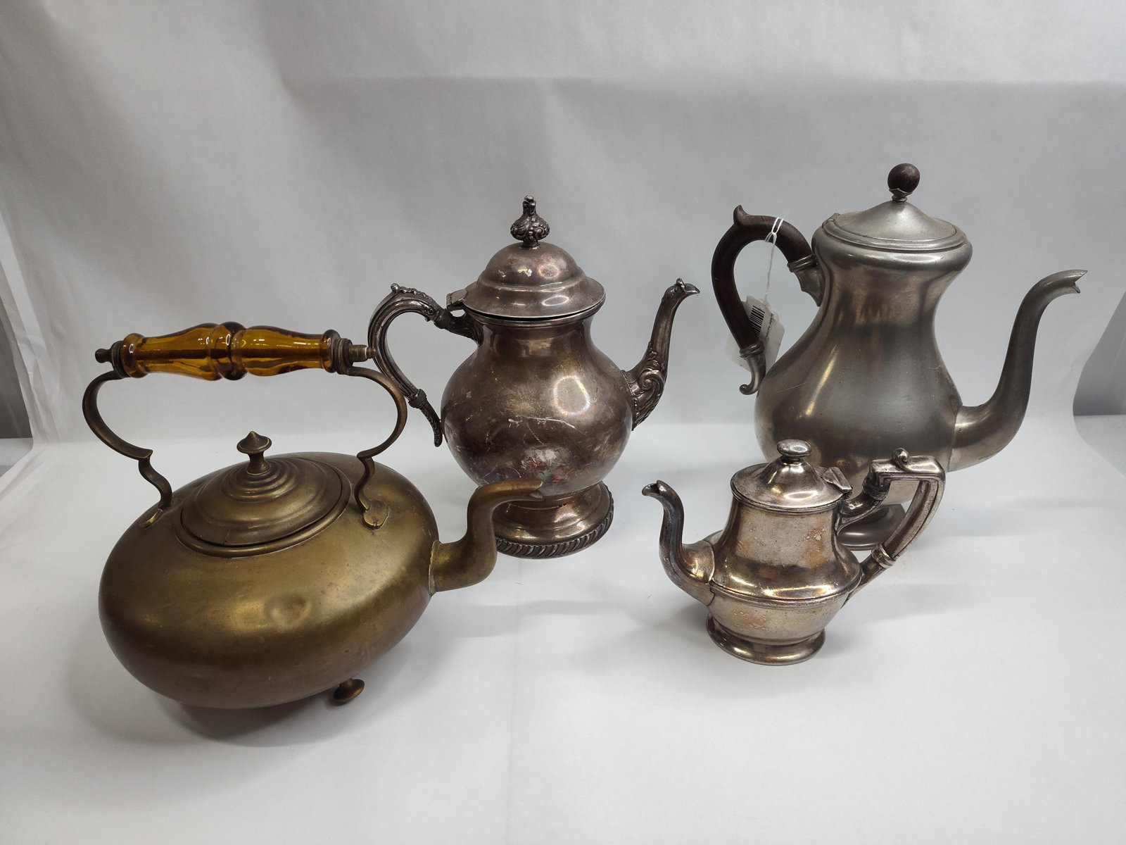 Silver, Pewter & Brass Tea & Coffee: A collection of metal holloware comprising items of varying materials and forms. Included is a rounded brass kettle featuring a three-footed base and a distinctive amber-colored faceted handle. A