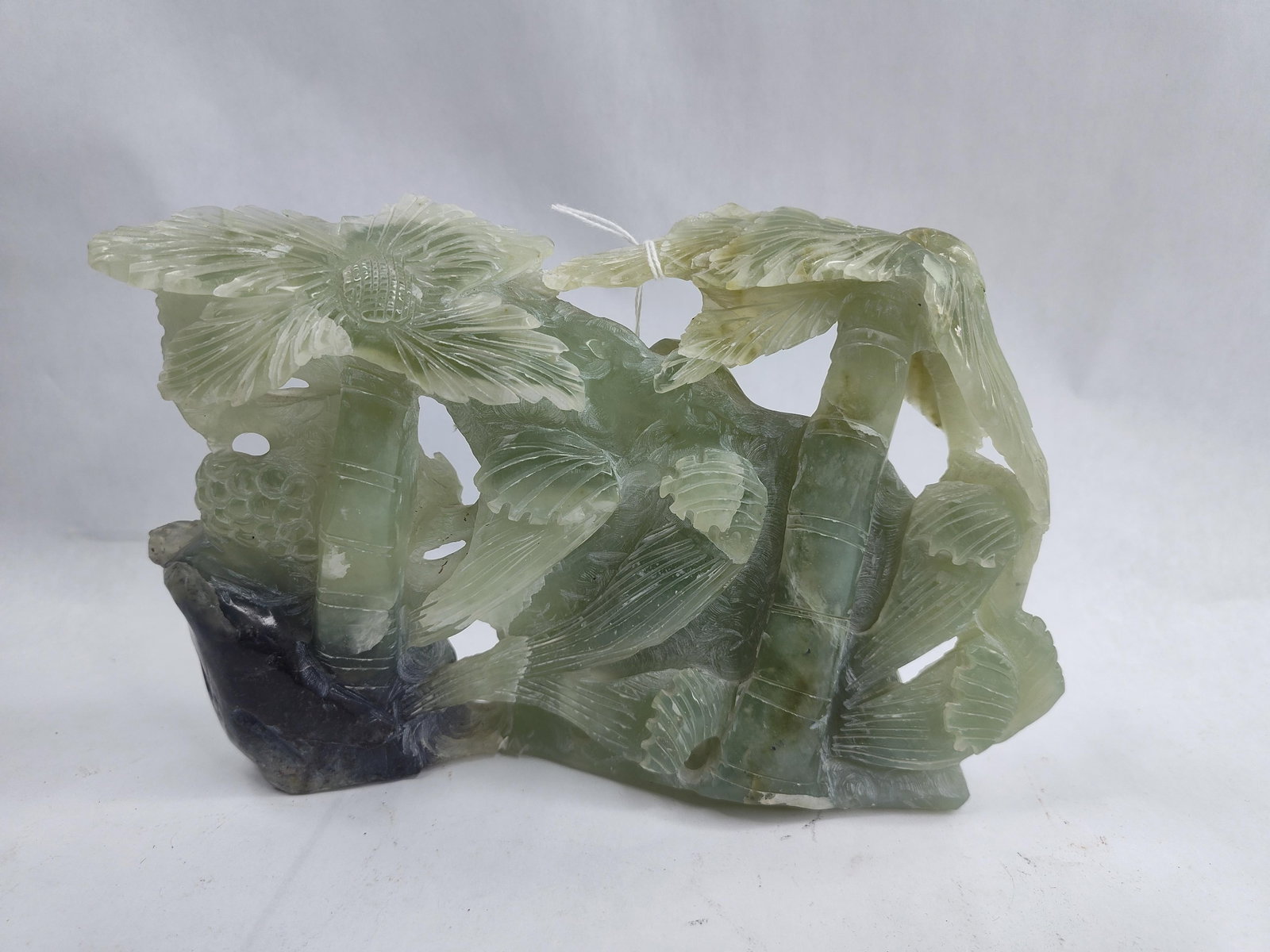 Chinese Hardstone Elephant Carving: This hand-carved sculptural group is fashioned from a pale celadon green hardstone, possibly nephrite or serpentine, exhibiting areas of translucency throughout the composition. The work is carved in