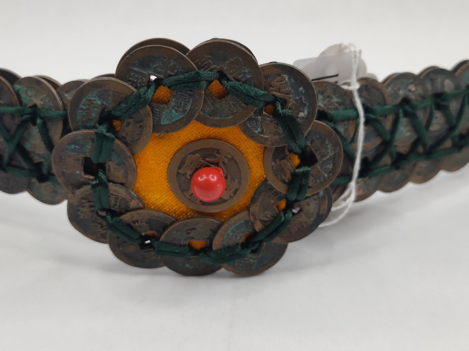 Chinese Cash Coin & Cinnabar Style Belt: This ornamental belt is constructed from numerous circular copper-alloy Chinese cash coins. The coins are arranged in a multi-row lattice and secured with an intricate network of dark green braided