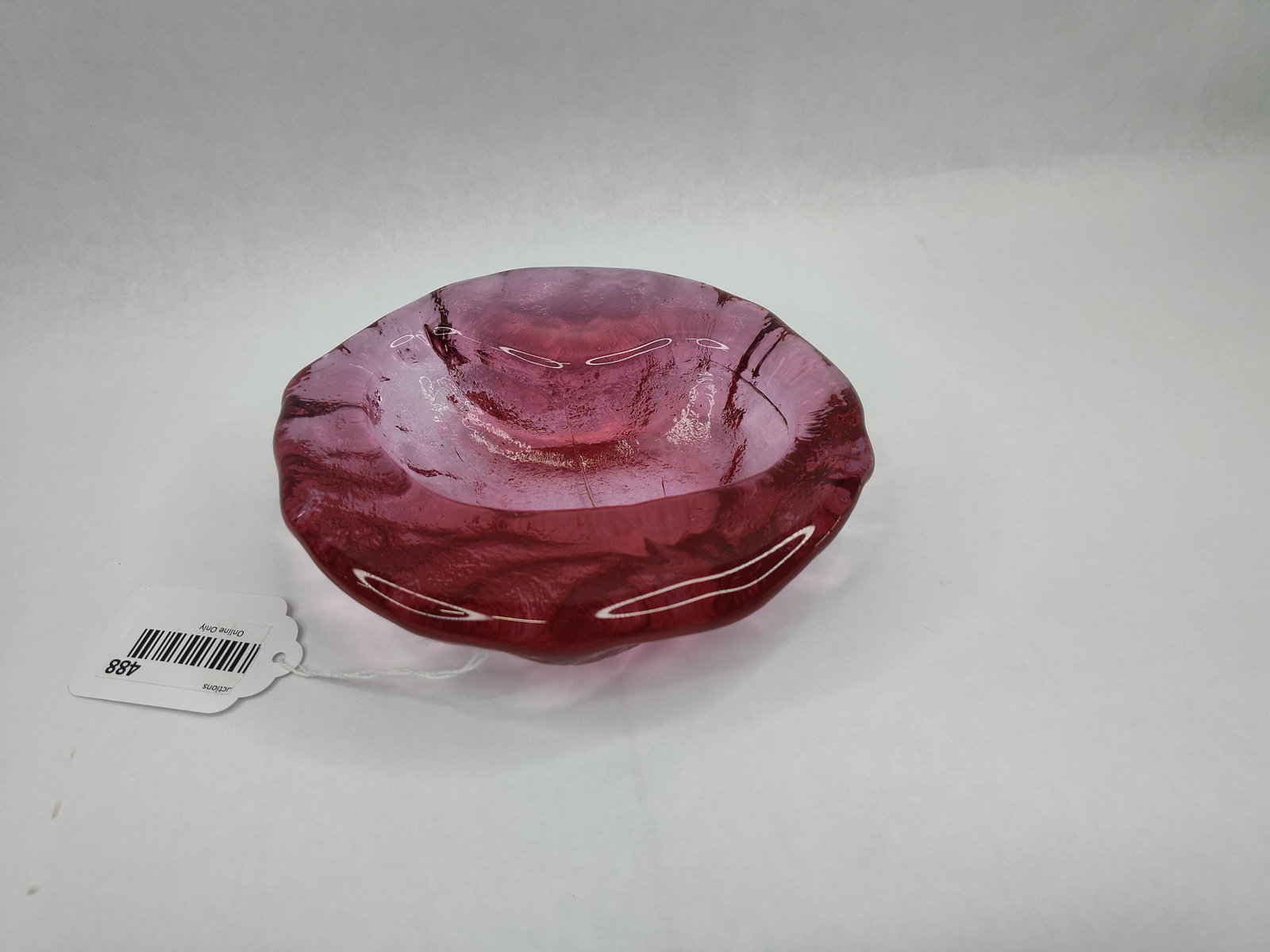 MCM Cranberry Textured Glass Bowl: A heavy art glass bowl featuring a translucent cranberry red to ruby hue. The bowl is constructed with thick, rounded walls that deepen in color toward the base. The exterior surface exhibits a
