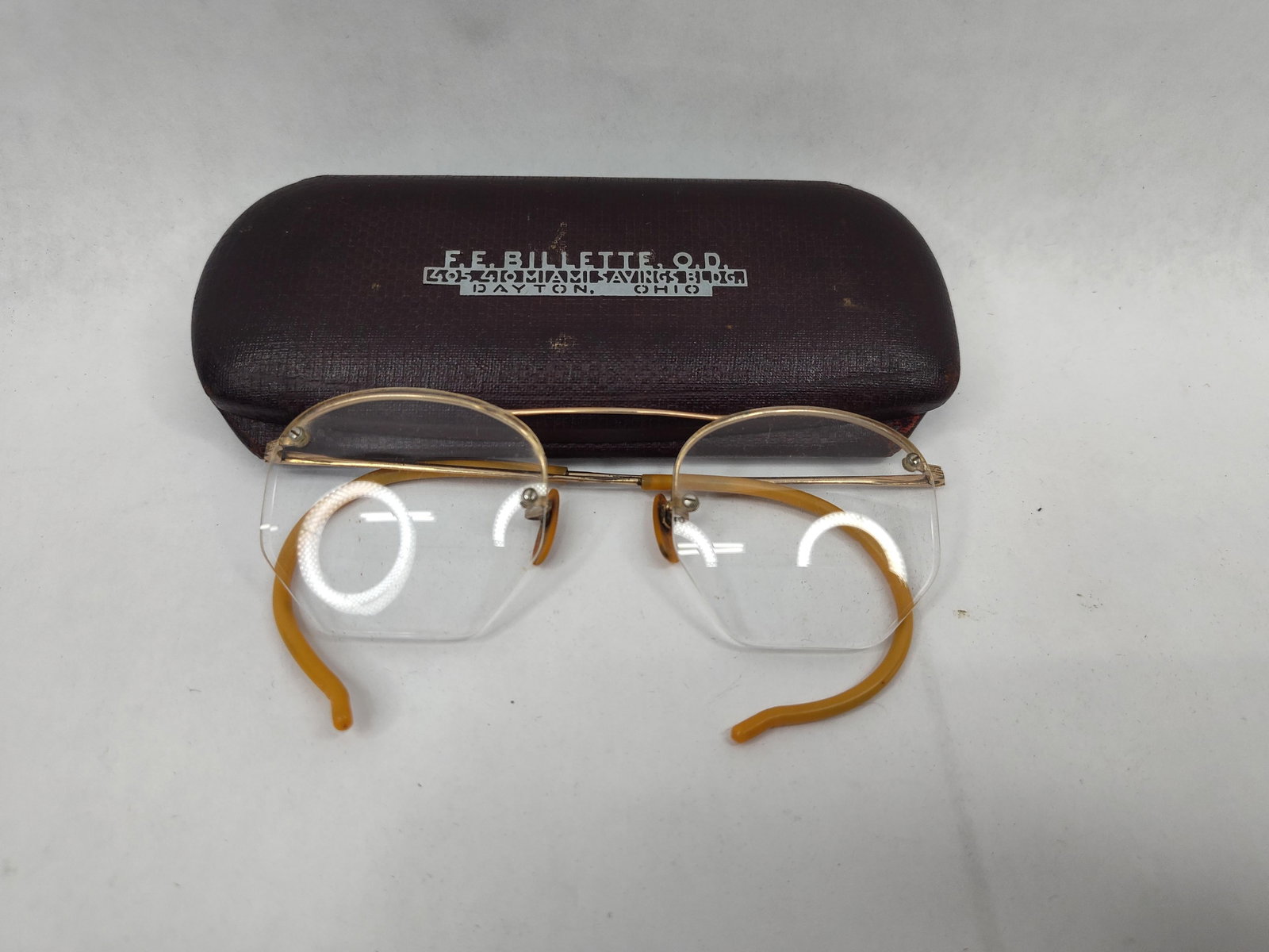 Pair Mid-C. 12K Gold Filled Eyeglasses: A pair of mid-twentieth century rimless eyeglasses featuring a gold-toned bridge and reinforced brow bar. The bridge is impressed with the characters 1/10-12K G F, indicating 1/10 12 karat gold-filled
