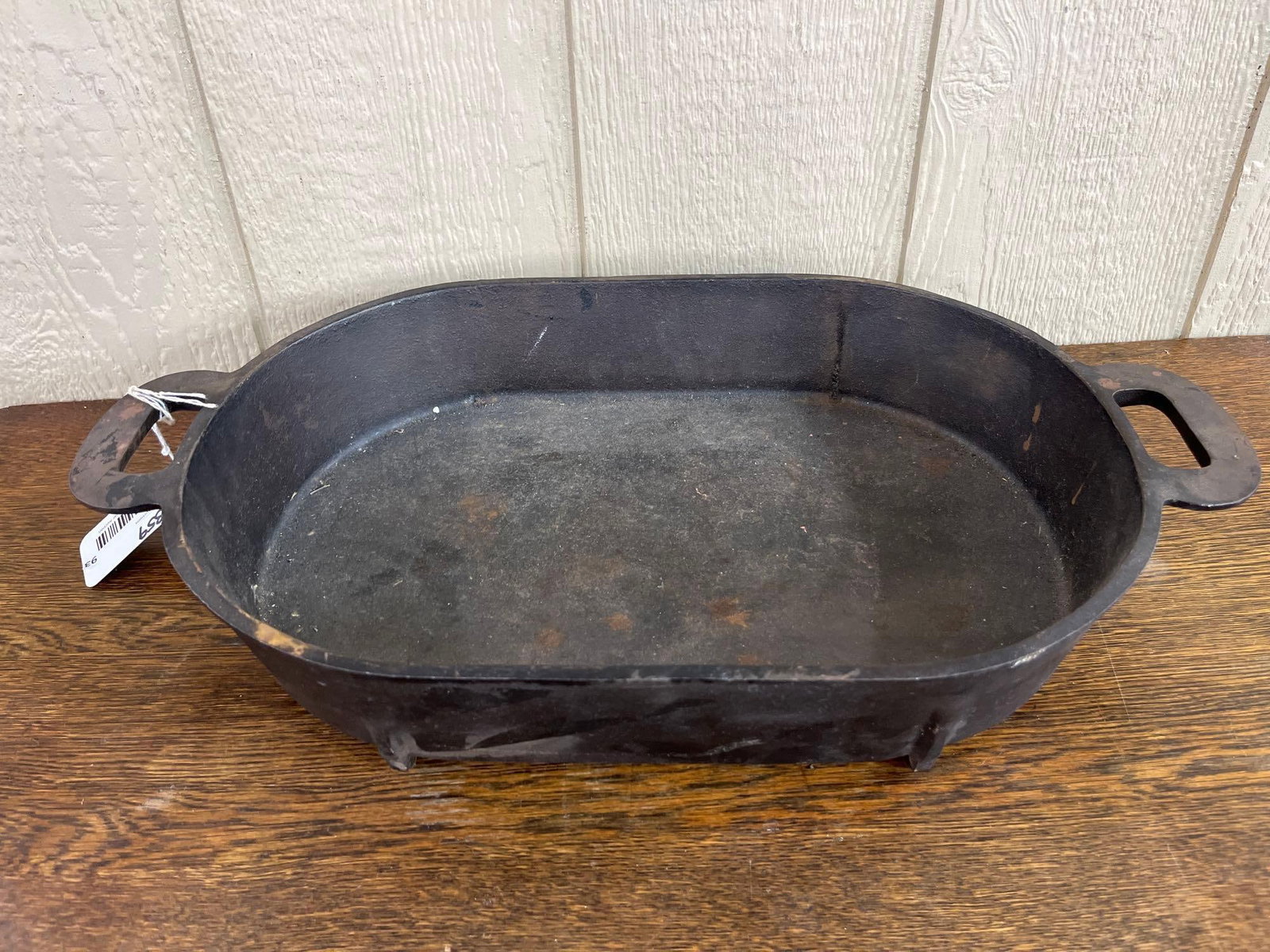 Cast Iron Oval Roaster with Grid: A cast iron oval roaster featuring two integrated open-loop handles and an embossed grid-reinforced underside. The body is deep with rounded ends, and the reinforced base is divided into six rectangul