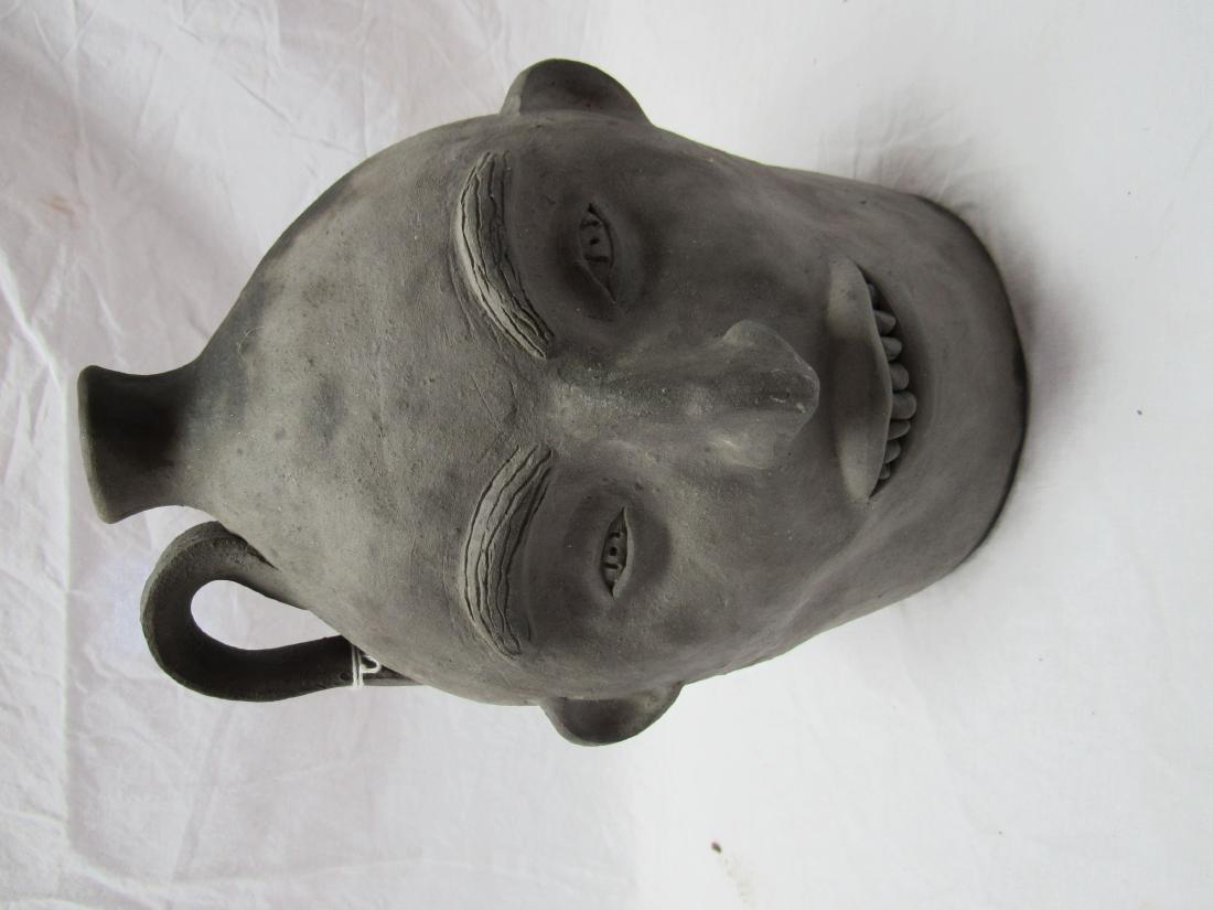 Clint Alderman Double-sided Face Jug: Clint Alderman Double-sided Face Jug. Jug depicts smiling face on one side and upside down face on the other. Bottom reads "Mud Creek Pottery, Cornelia, GA. December 1998 by Clint Alderman". Jug belie
