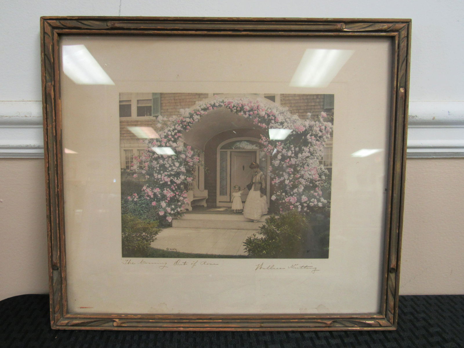Wallace Nutting "The Coming Out of Rosa" Hand Colored: Wallace Nutting "The Coming Out of Rosa" Hand Colored Photograph. Circa 1915-1925. Depicts child, Rosa, holding mother's hand on rose bordered porch. Very good condition with some stains to matte. Sev