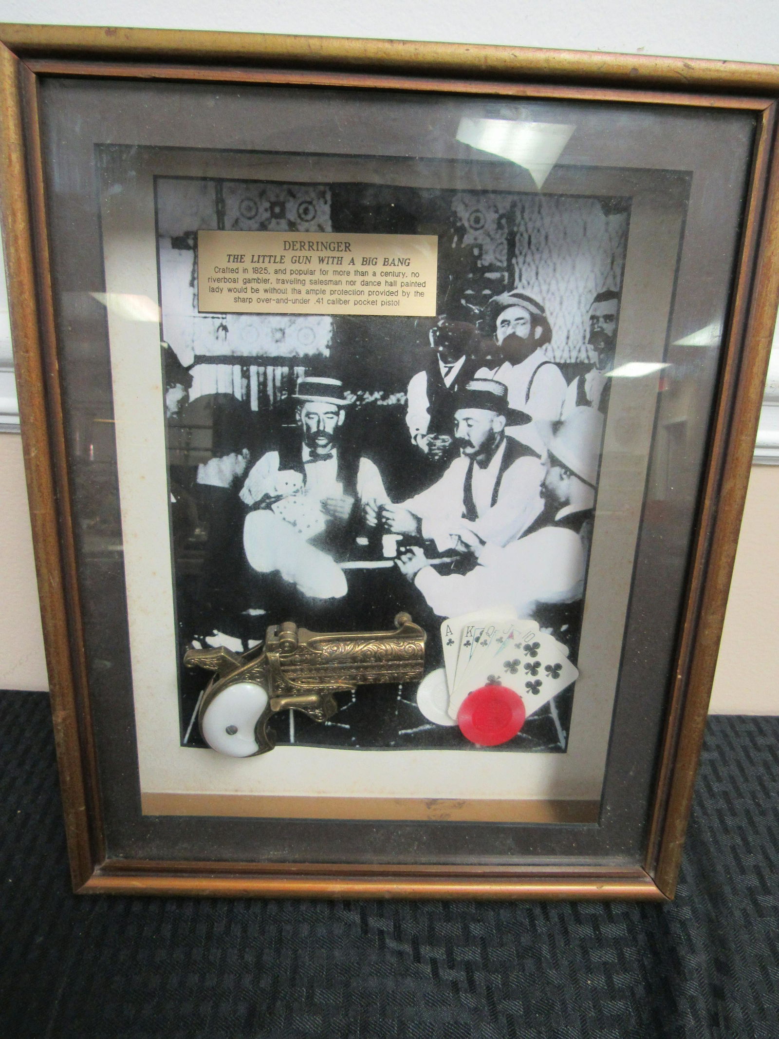 Vintage Derringer Shadow Box: Vintage Derringer Shadow Box. Contains print of men gambling with movie prop derringer and plaque that explains history of derringer. Some water damage to print. 12.5" x 16"