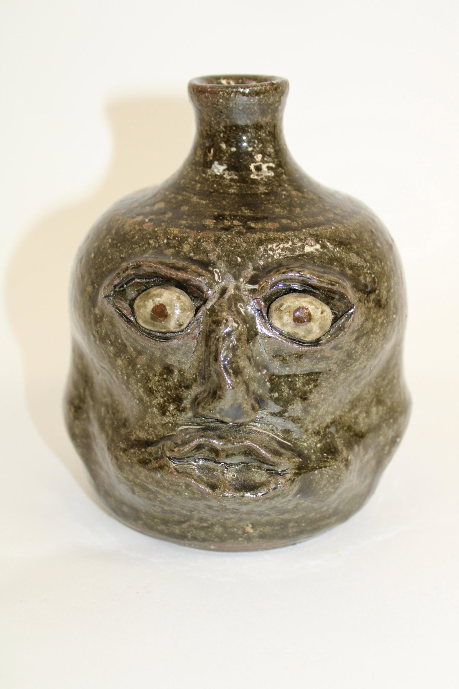 David Meaders (1950-2019) Face Jug.: David Meaders (1950-2019) Face Jug. Signed David Meaders. Marked #21. Jug in very good condition with alkaline glaze. Handle is missing, as photographed. Measures 6.5".