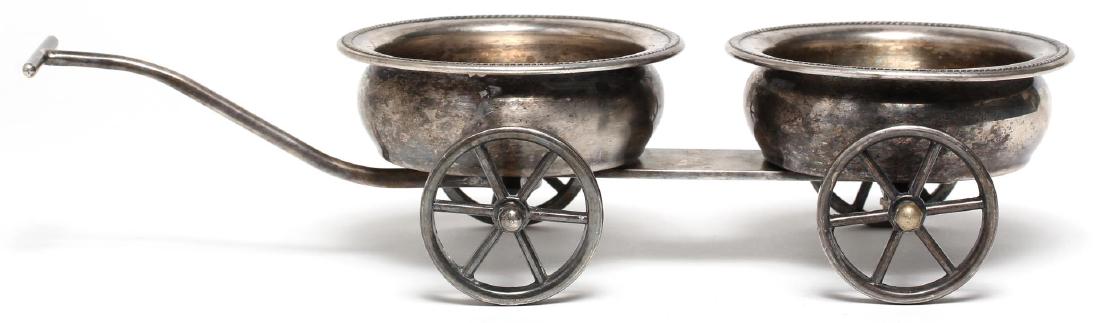 F.B. Rogers Silver-Plated Tabletop Wine Trolley: The two flat-bottom cups with gadroon rims, one for red and one for white, mounted on a diminutive rolling cart; maker's mark on the underside. 3" H X 13" L X 5.5" W.