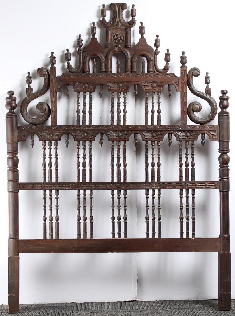 Mexican Hand-Carved Reredo Screen Headboard: With numerous turned spindles supporting floral-carved bands, two large S-scrolls flanking, and a number of urn finials. 75" H X 53.3" W. Lacking uppermost finial, top arcade with old shrinkage crack.
