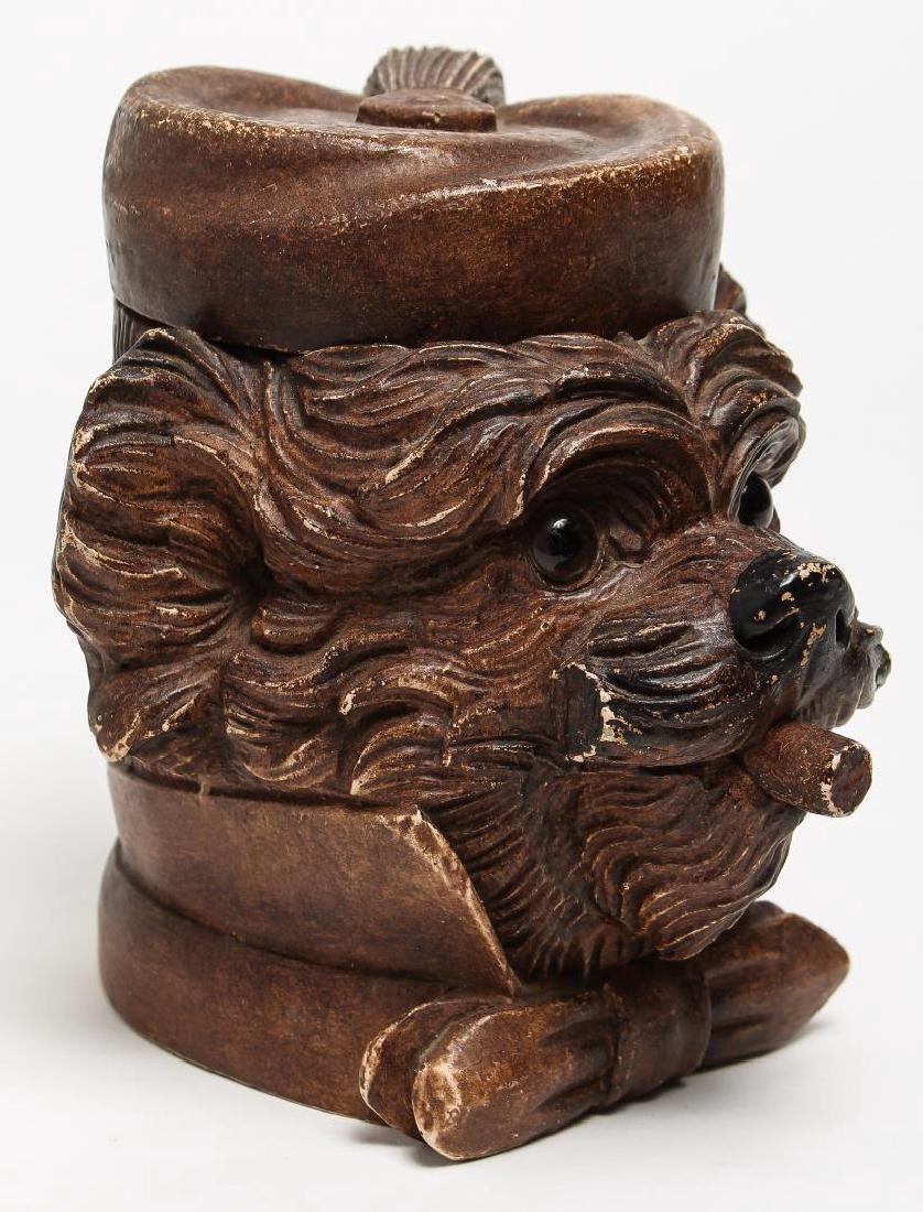 Continental Carved Wood Dog's Head Tobacco Jar: Vintage 1920s, in the form of a terrier smoking a cigar, the underside with a label from John Roselli Antiques. 7" H. Loss to inner rim; minor wear to paint on some edges.