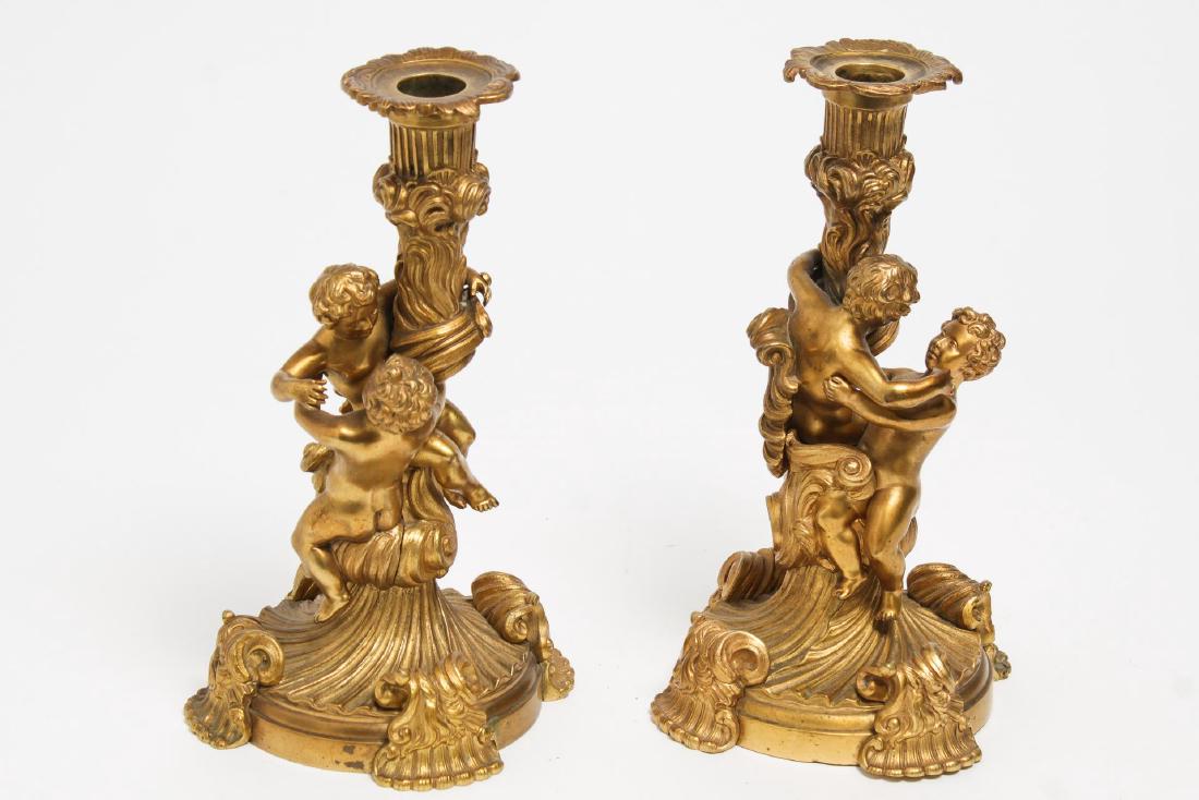 Louis XV Rococo-Style Gilt Bronze Candlesticks: French Louis XV-style ormolu gilt bronze figural candlesticks decorated with putti. 8.75" H X 5.25" diameter. Putti and one bobeche need securing.