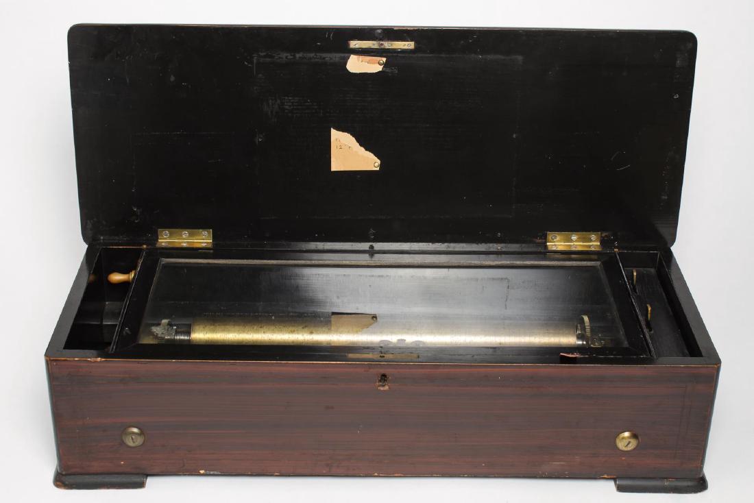 Swiss Antique Music Box, 9-Tune, in Marquetry Case: Swiss large cylinder music box playing multiple tunes, antique circa 1870s-1880s, in inlaid wood marquetry case. 26.25" L. Age-appropriate wear to case; box plays but may require calibration.