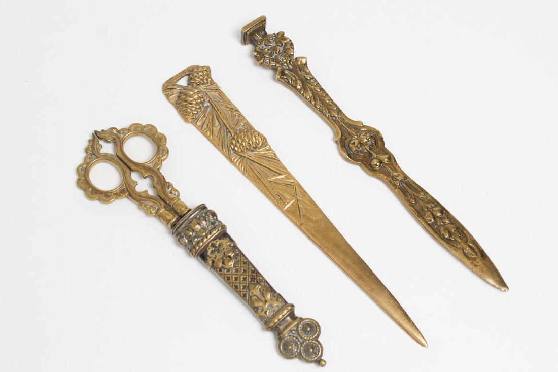 Desk Set Items, Art Deco & Other Brass, Vintage: Desk articles, an Art Deco polished brass pinecone letter opener, Neoclassical-style signet, and Rococo-style scissors in half-case. Longest: 8.5" H.