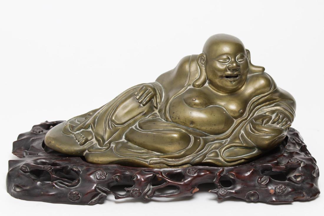 Chinese Laughing Buddha Hotai Figure, Gilt Bronze: Cast bronze Chinese/ Asian Hotai or Laughing Buddha, reclining, on carved wood stand. On stand: 9.25" H X 18" W X 9.25" D. Minor patina and soiling to recessed areas; some old breaks to stand.
