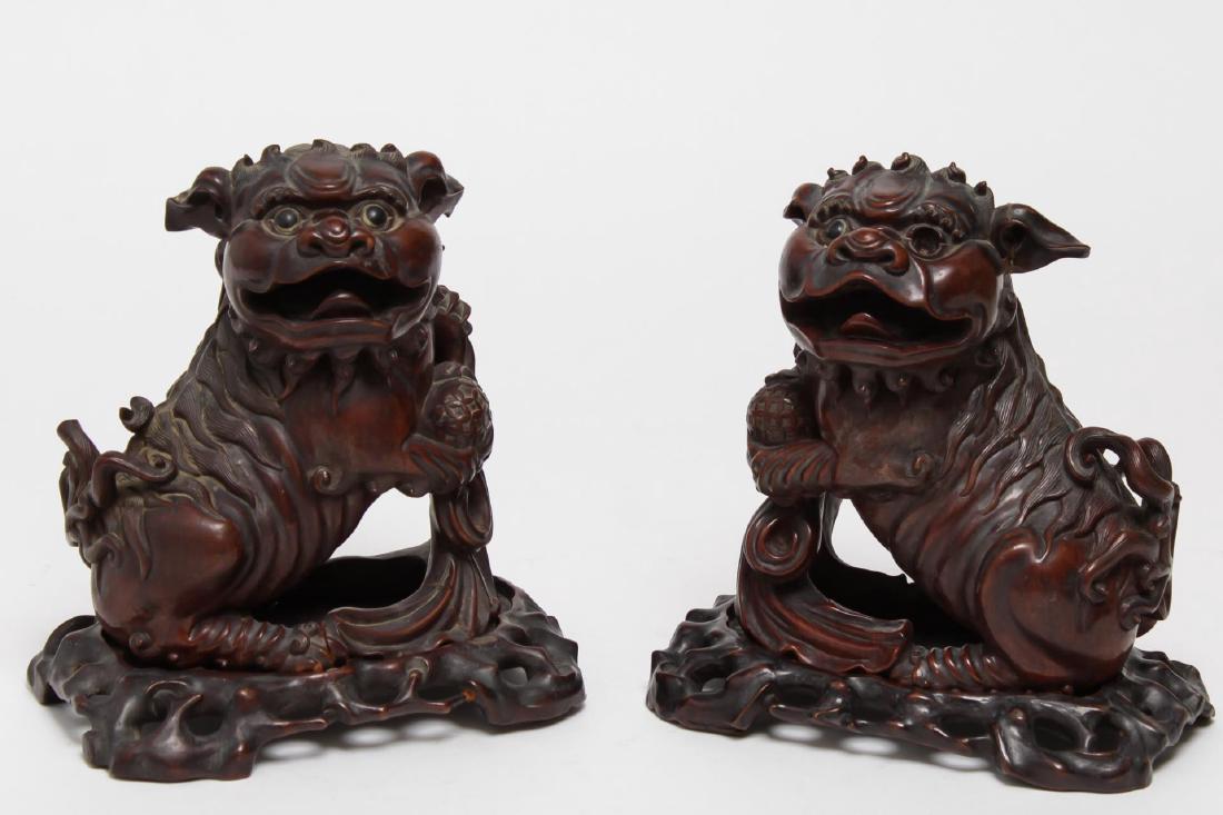 Chinese Foo Dogs, Carved Wood with Glass Eyes: Chinese wood foo lions or dogs, pair on carved bases, inset with glass eyes; Asian art. Each: 8.5" H (on stand). Some splitting, a few repairs and losses, lacking one eye.
