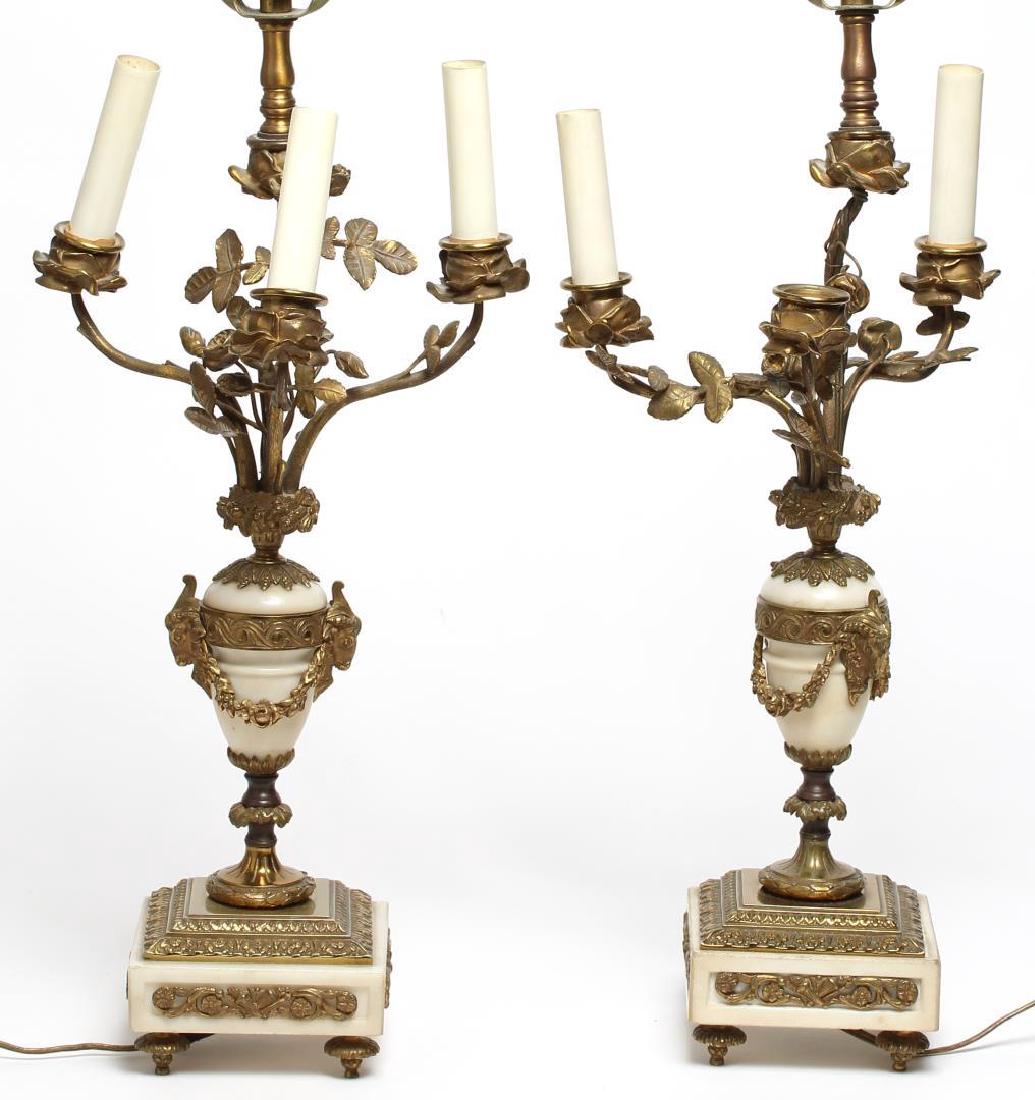 Neoclassical Lamps, Bronze & White Marble Urn-Form: Neoclassical candelabra lamps, gilt bronze ormolu and white marble, French-style, with motifs of rose buds and rams' heads. 29" H (to finials). Lacking one faux-candle, arms slightly bent out of symme