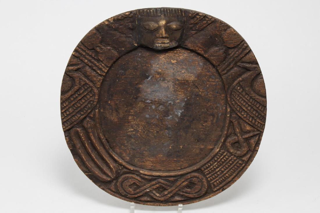 African Yoruba Carved Wood Divination Tray: African Yoruba tribal ethnographic carved wood divination tray, Nigeria, the antique round board with geometric border centering an image of the trickster diety Eshu. 12.75" diameter. The surface with