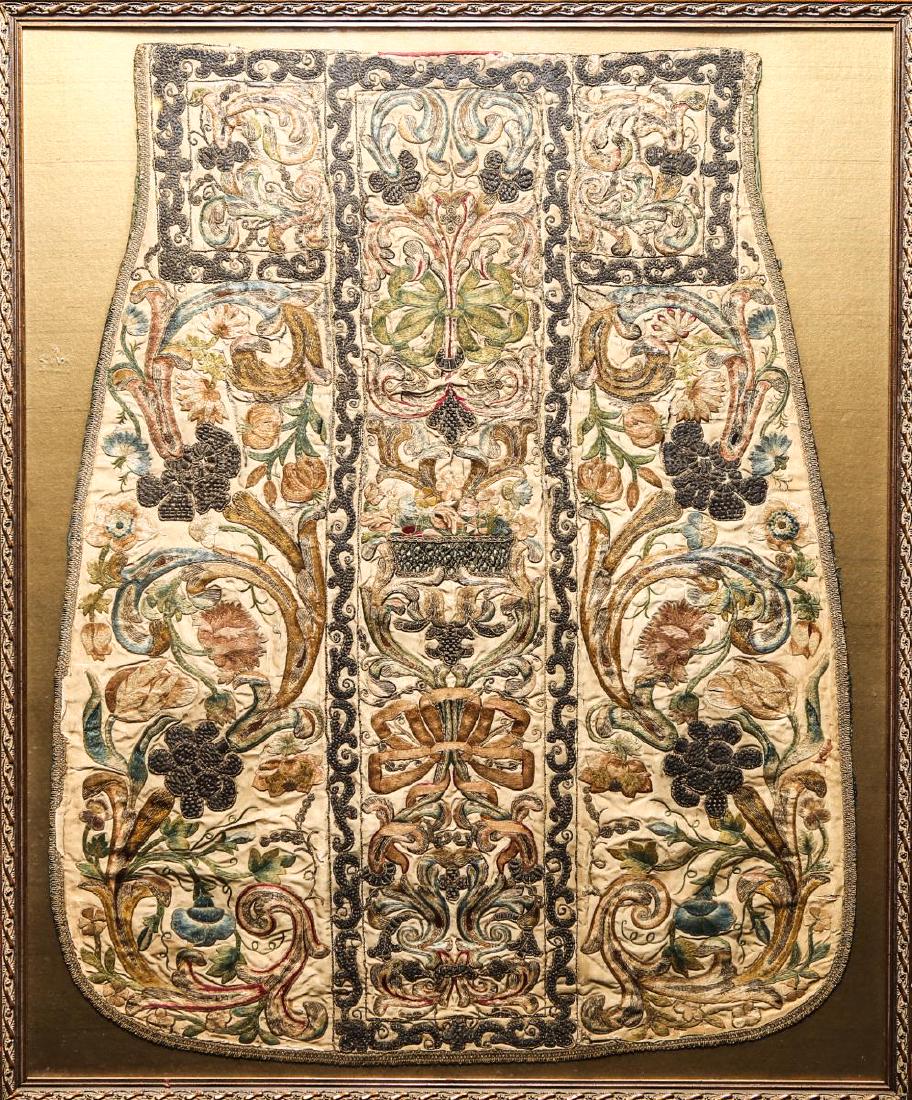 Continental Catholic Liturgical Chasuble, Antique: Continental Catholic liturgical embroidered chasuble, antique bell-form with various floral motifs in red, blue and green in gold-tone threaded border. Embroidery: 32" H X 25" W; frame: 35.25" H X 29.