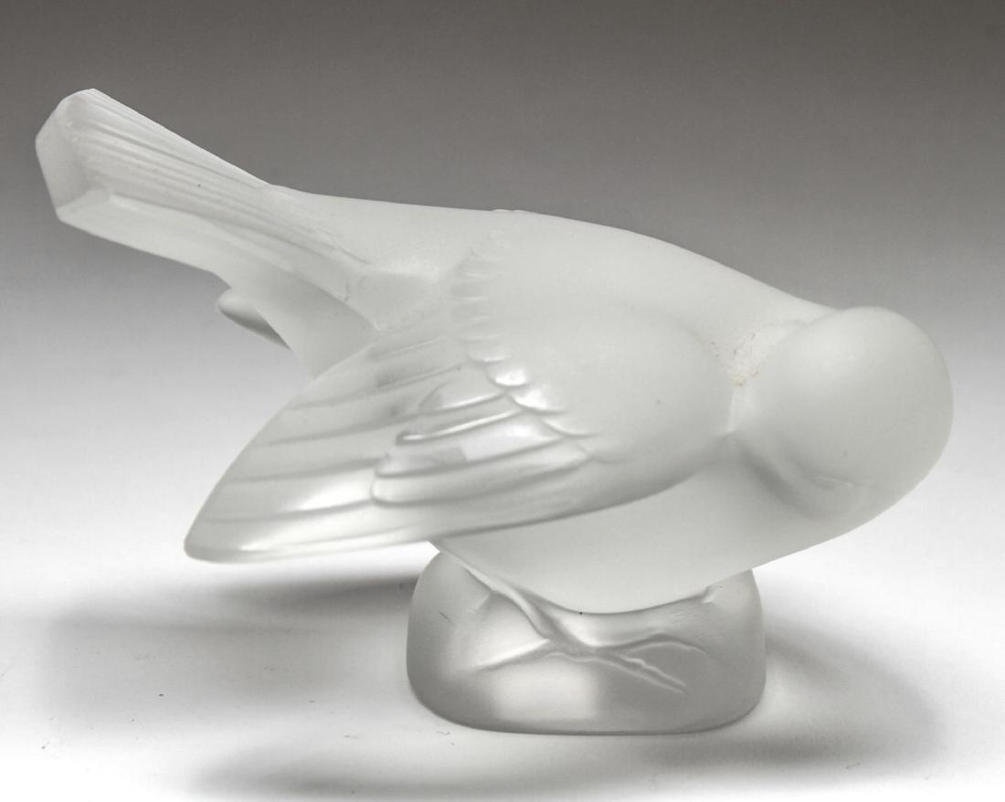 Lalique Crystal "Coquet" Sparrow Sculpture: Lalique colorless satin crystal "Coquet" sparrow figurine, the little bird with its head coyly turned, the underside acid-etched "Lalique ® France," and with an old price sticker. 3.25" H X 5.25" L.
