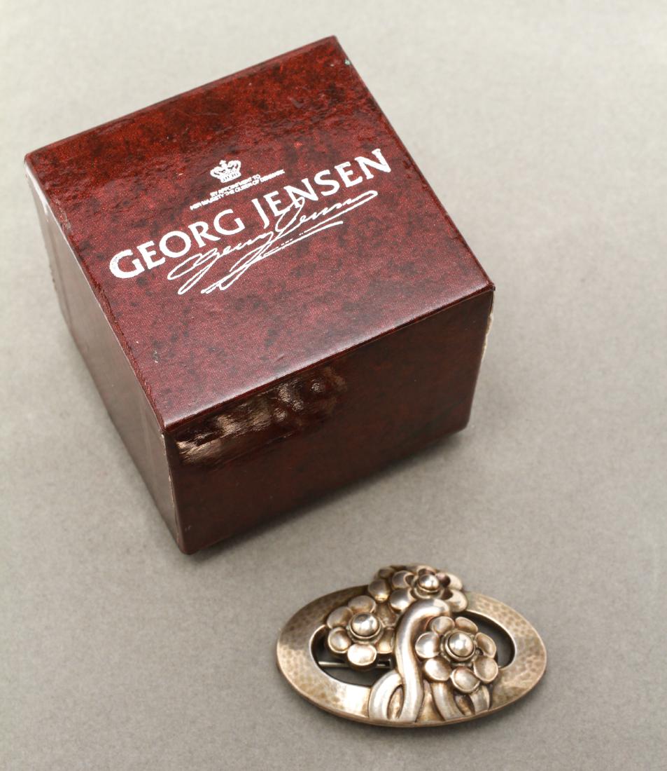 Georg Jensen Danish Sterling Silver Brooch: Georg Jensen Danish sterling silver brooch, open-work oval and flower motif, marked: Georg Jensen / Denmark / Sterling / 28," includes Georg Jensen box. 2" W x 1.5" D. approx .43 ozt.