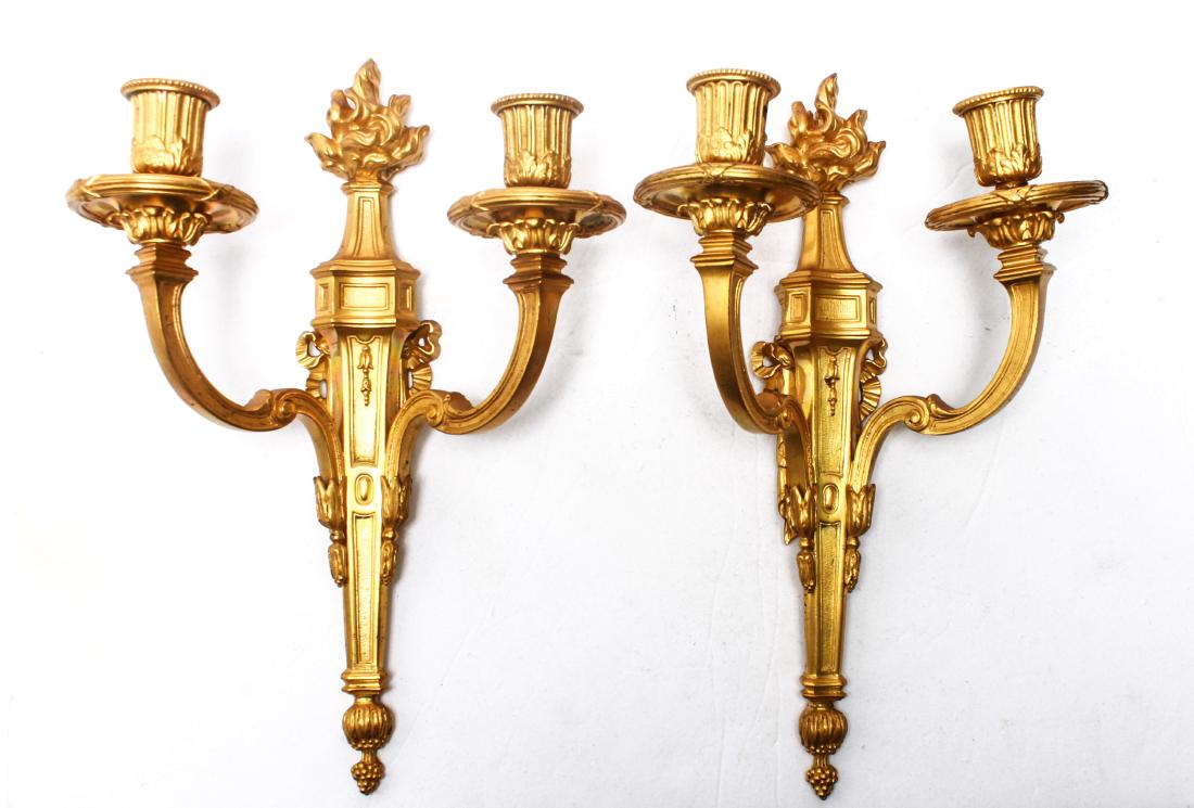 Neoclassical Manner Bronze Sconces, Pair: Neoclassical manner gilt bronze sconces, two arms each bearing single candleholder, with torch, acanthus, husks, and ribbon elements. 16" H x 11 W x 6" D.