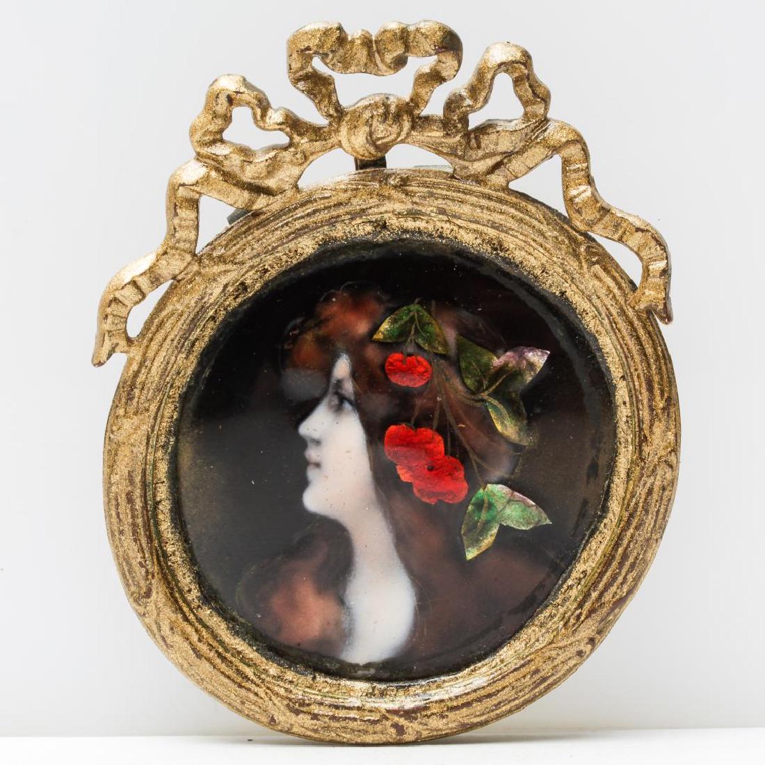 Antique Enamel Portrait Pendant of Woman: Enamel portrait of a woman in profile, cameo-manner, wearing cherries in her hair, antique, likely Edwardian, frame mounted with a hanging loop. 3.5" H. Minor wear throughout.