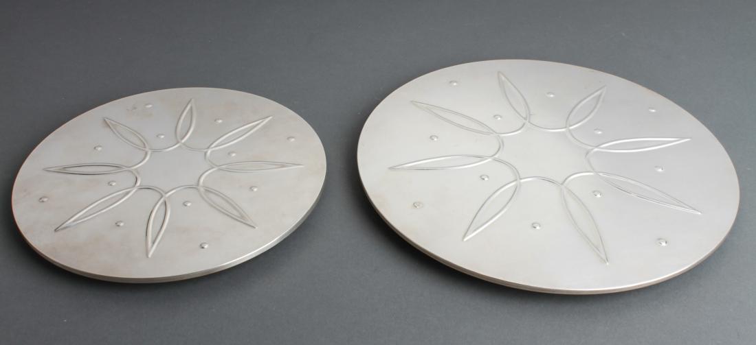 Towle Sterling Silver Clad Footed Trivets, 2: Towle sterling silver clad trivets, two, repousse geometric motif, both marked "Towle Sterling," both with paper maker's label underside. Larger: 10" diameter. Not weighable.