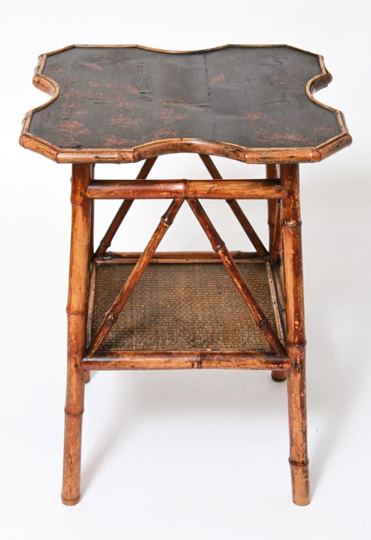 Aesthetic Movement Chinoiserie Lacquered Table: Aesthetic Movement occasional table, shaped top with Chinoiserie manner lacquered decoration with bamboo-form frame, rattan lined stretcher shelf. 28.75" H x 21.25" square. Minor splitting in lacquere
