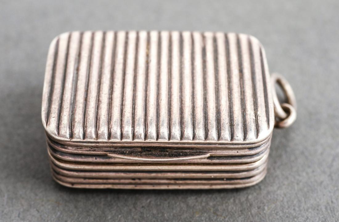 English Silver Vinaigrette w Floral Pierced Grille: English sterling silver vinaigrette, ribbed case, an interior hinged engraved gilt-silver pierced grille with floral motif, gold-wash interior, indistinctly hallmarked on edge. 0.25" H x .875" W x .62