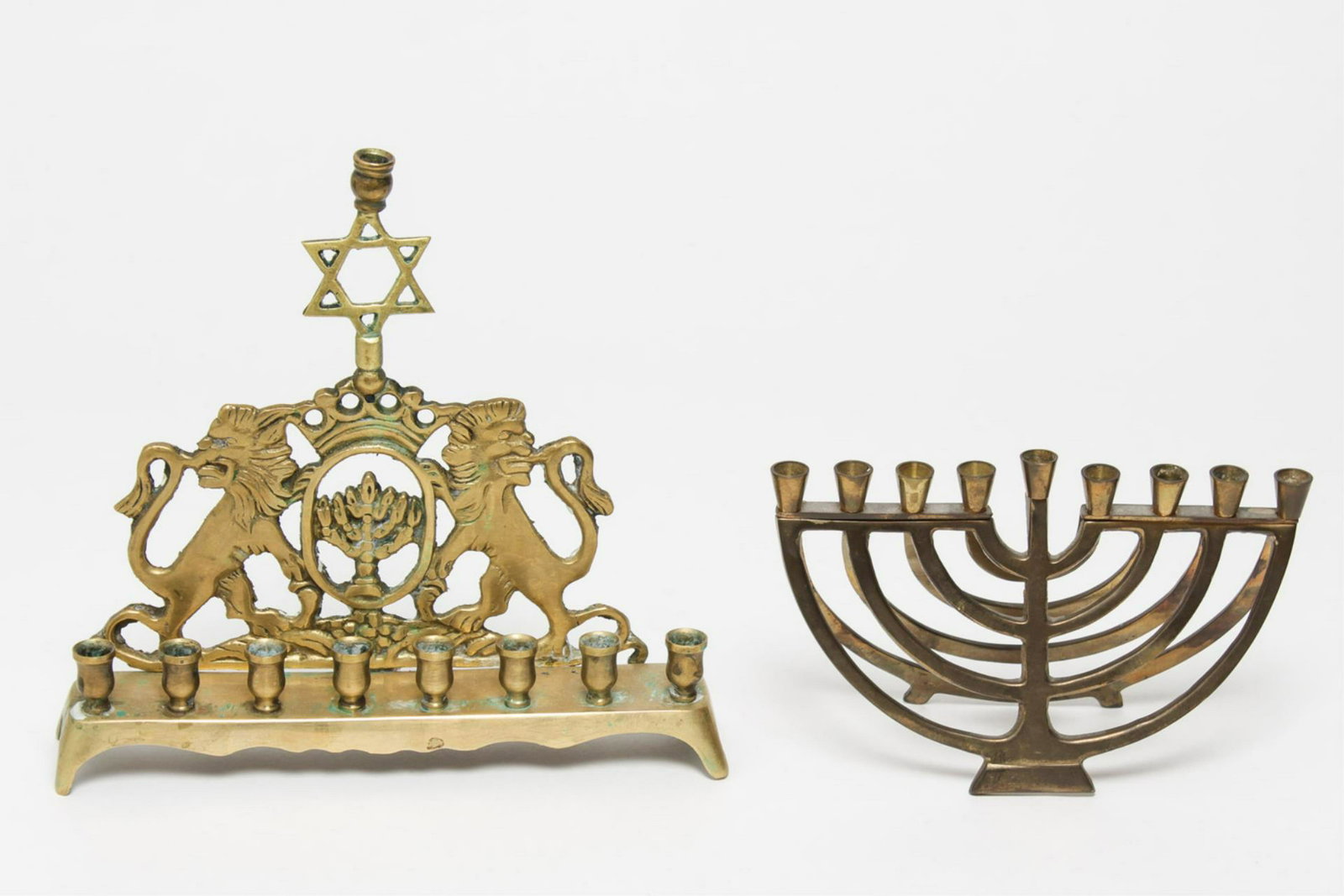 Judaica Hanukkah Brass Menorahs, 2: Judaica Hanukkah eight-light gilt brass menorahs, the first Modernist design with central shamash, the second traditional, with the Lions of Judah crowned by a Star of David topped with the shamash, t