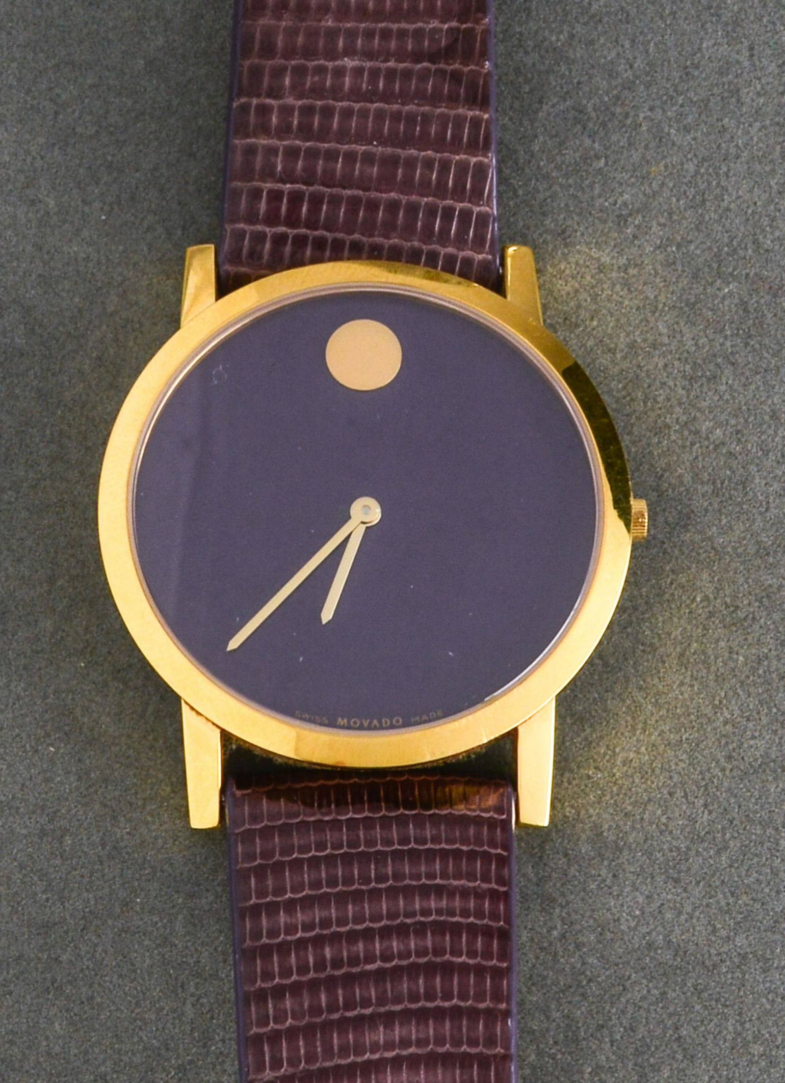 Movado Gold-Tone & Purple Dial Watch: Movado gold-tone and purple dial watch, marked on reverse: "Movado / Swiss made / 88 G1 1852 / 8584302 / Stainless Steel Water resistant sapphire Crystal," with a Movado mauve lizard band. 43mm diamet