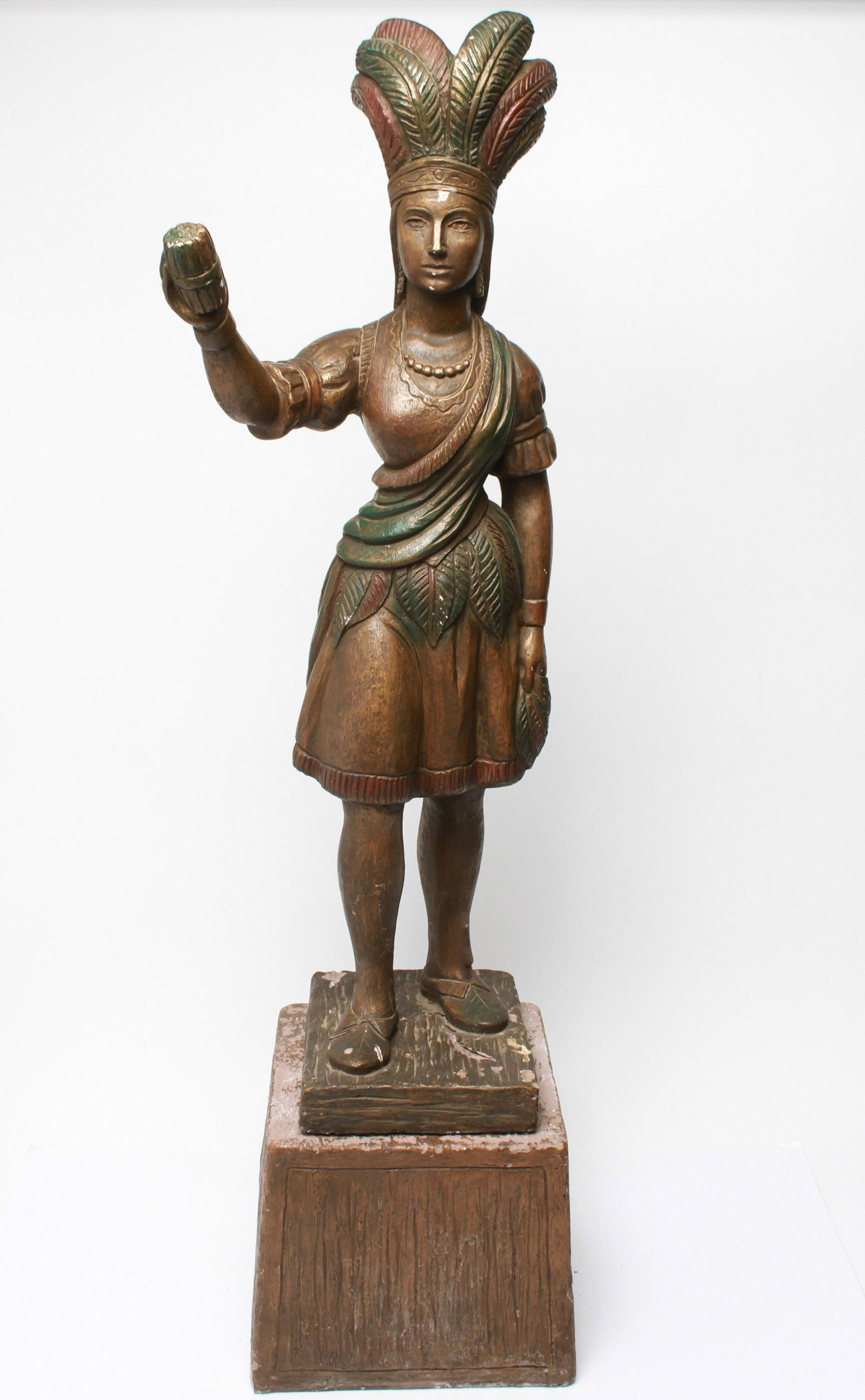 Cigar Store Indian Maiden w Headdress & Cigars: Cigar store figurative polychrome sculpture depicting an Indian maiden wearing a feather headdress and offering cigars on a separate plaster base. Sculpture: 38.75" H x 13" W x 13" D; base: 10.25" H x