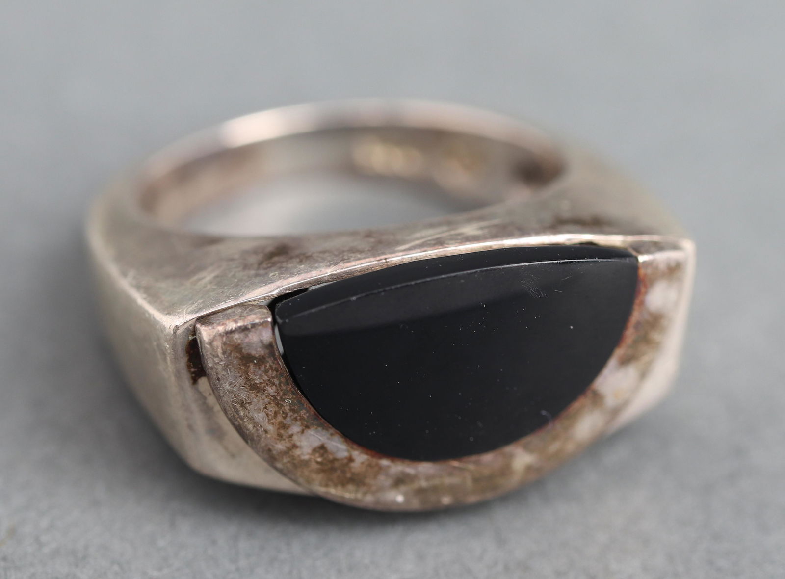 Movado Silver Onyx Unisex Ring: Movado silver and onyx unisex ring, stamped: "925," and with maker's mark. 0.875" L x 0.437" W at widest section. Ring size: 5 1/2. Approx. 0.26 ozt. inclusive.