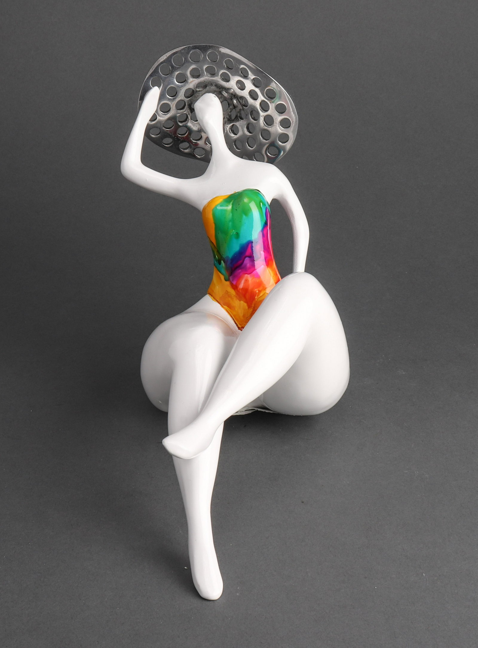 Ceramic Model Of A Sunbathing Lady: Ceramic model of a sunbathing lady, with painted swimsuit and pierced chrome hat, unmarked. 8" H x 10.25" W x 4.5" D.