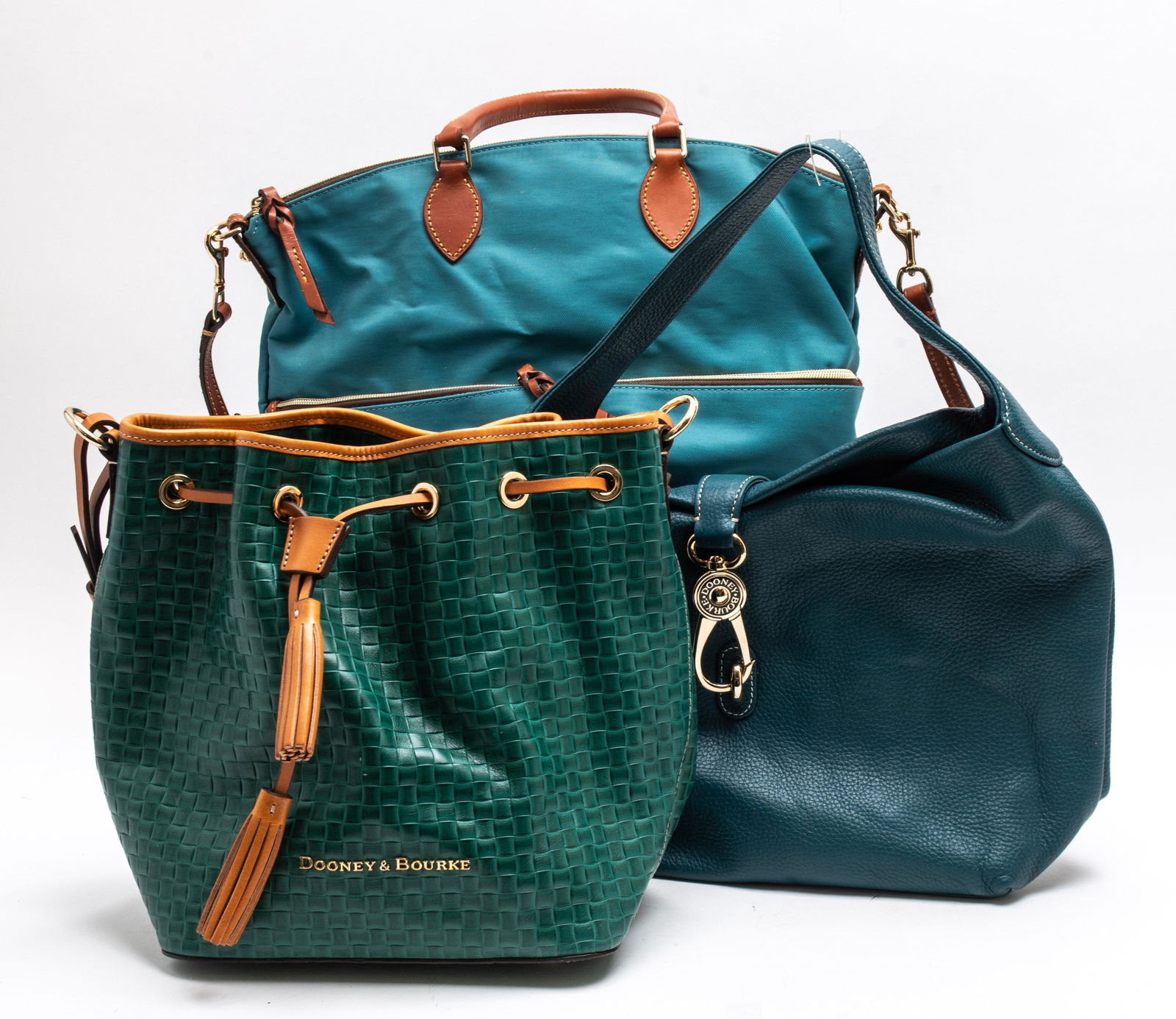 Dooney & Bourke Blue and Green Handbags, 3: Group of three Dooney and Bourke handbags, in hues of blue and green. Largest: 13” H x 12.5” W x 5.5” D.